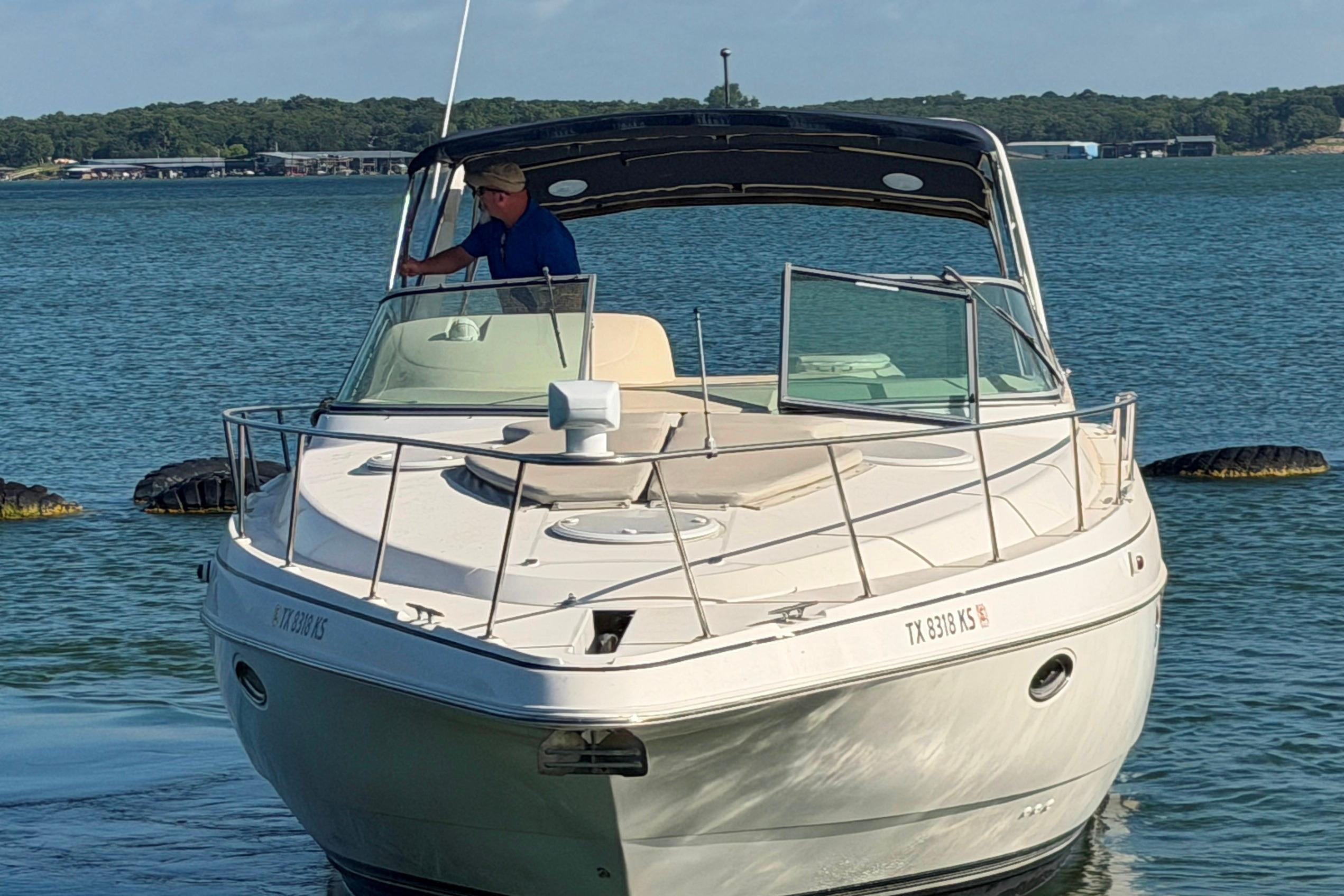 1997 Cruisers 3575 boat on water with person steering, scenic background.