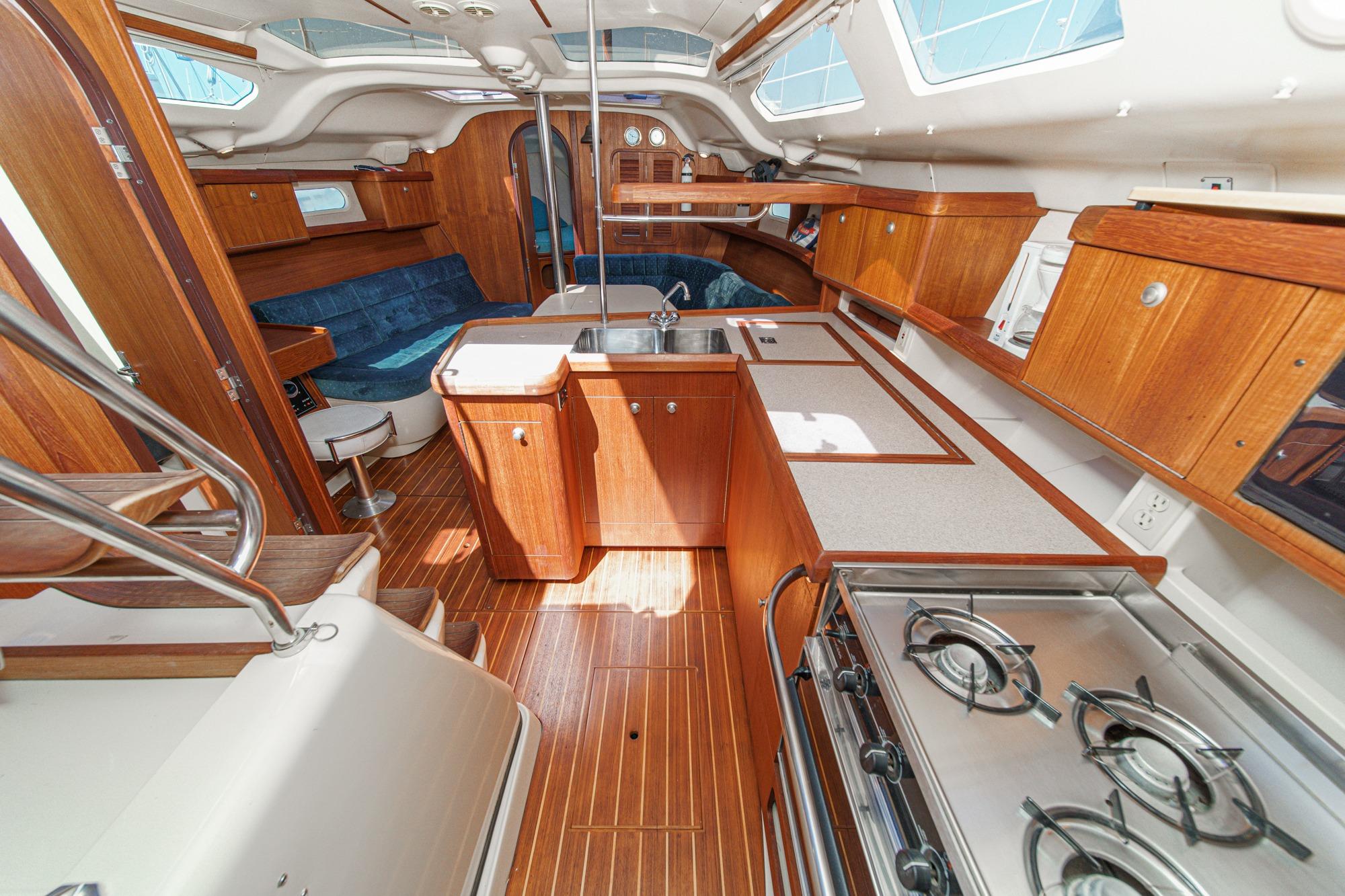 Interior of a 1996 Hunter 376 sailboat with wooden cabinetry and modern kitchen amenities.