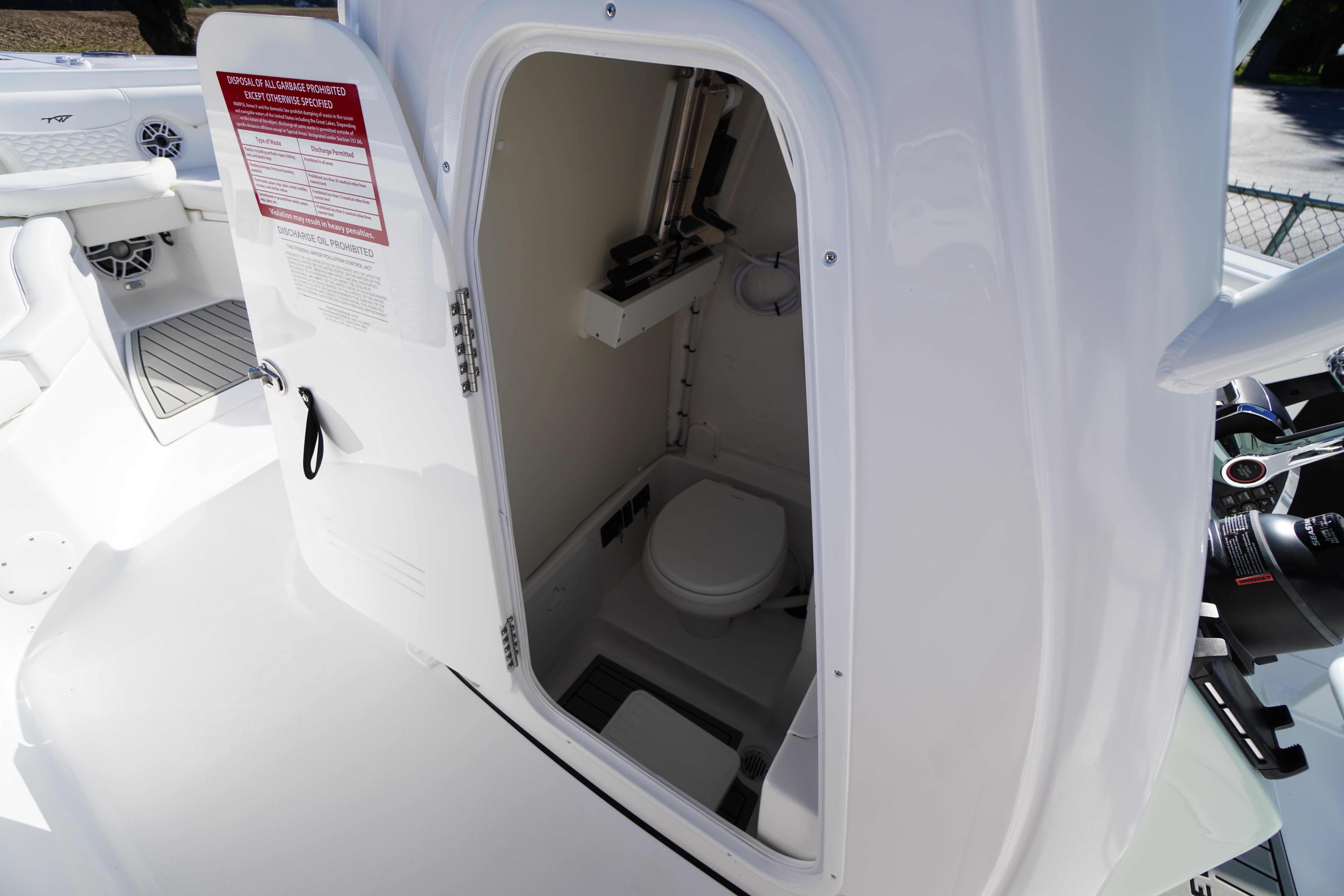 2026 Tidewater 272 LXF boat interior with open door revealing compact marine toilet.