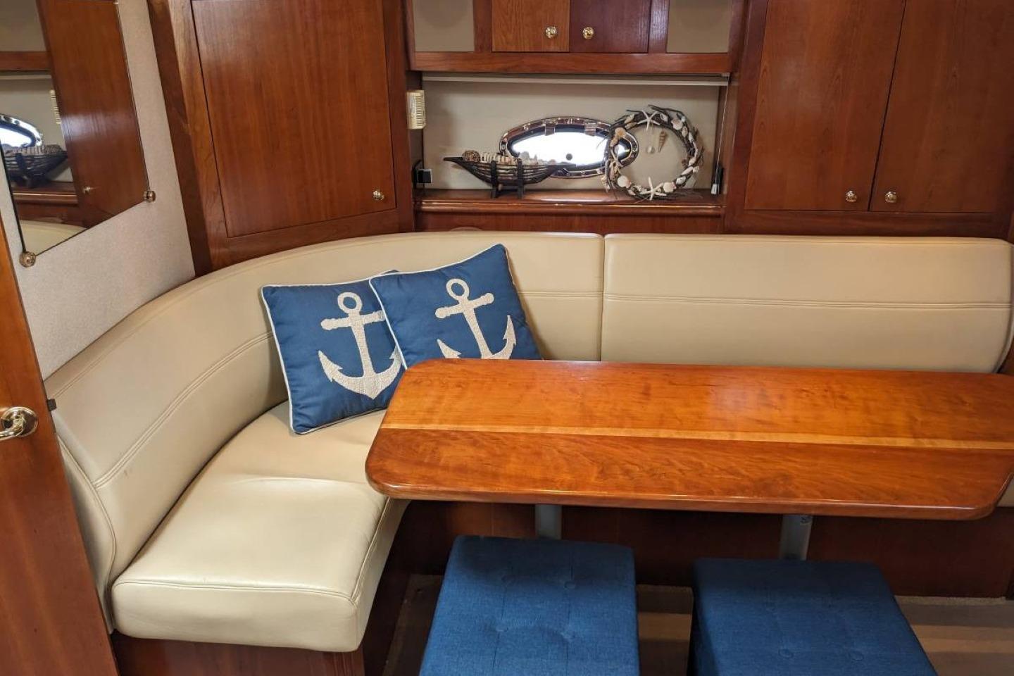 Interior of 2003 Cruisers 3970 yacht with wooden table and anchor-themed cushions.