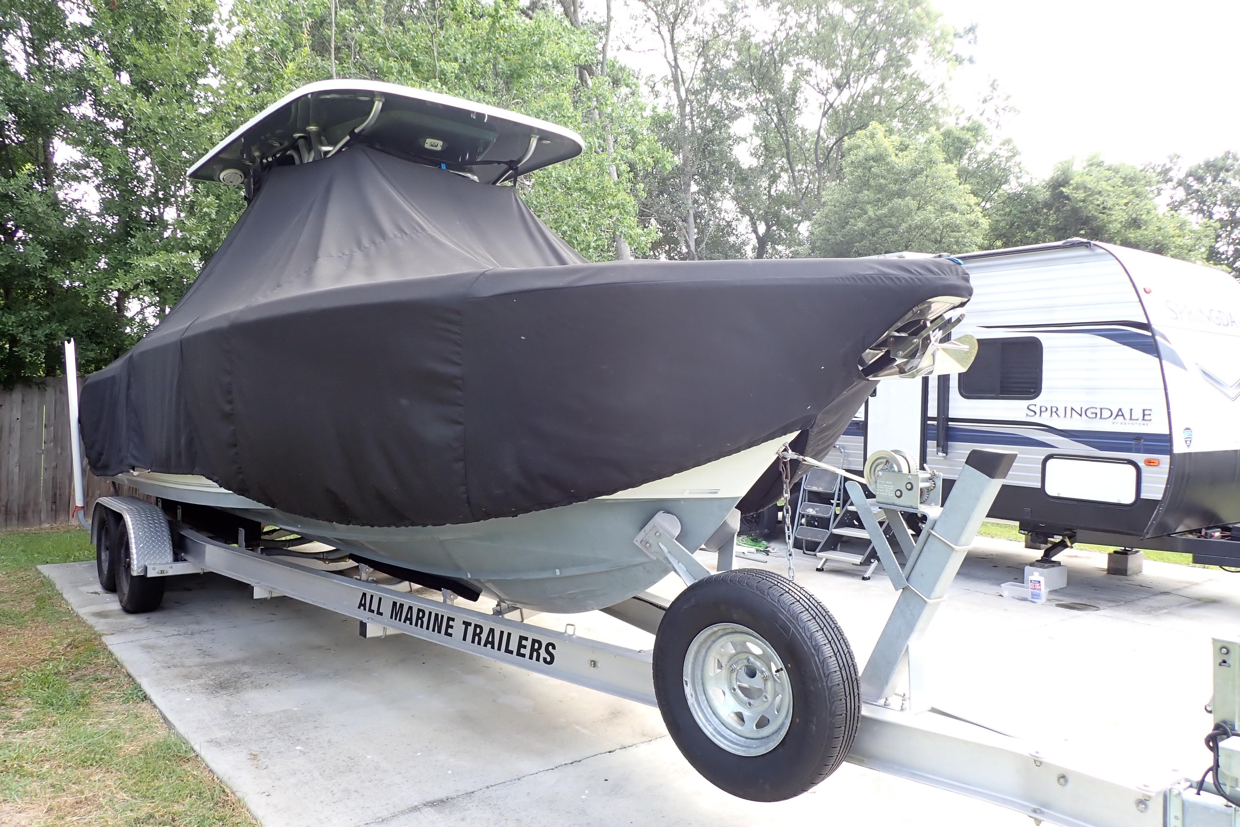 2019 Key West 263 FS boat covered on trailer, parked beside RV.