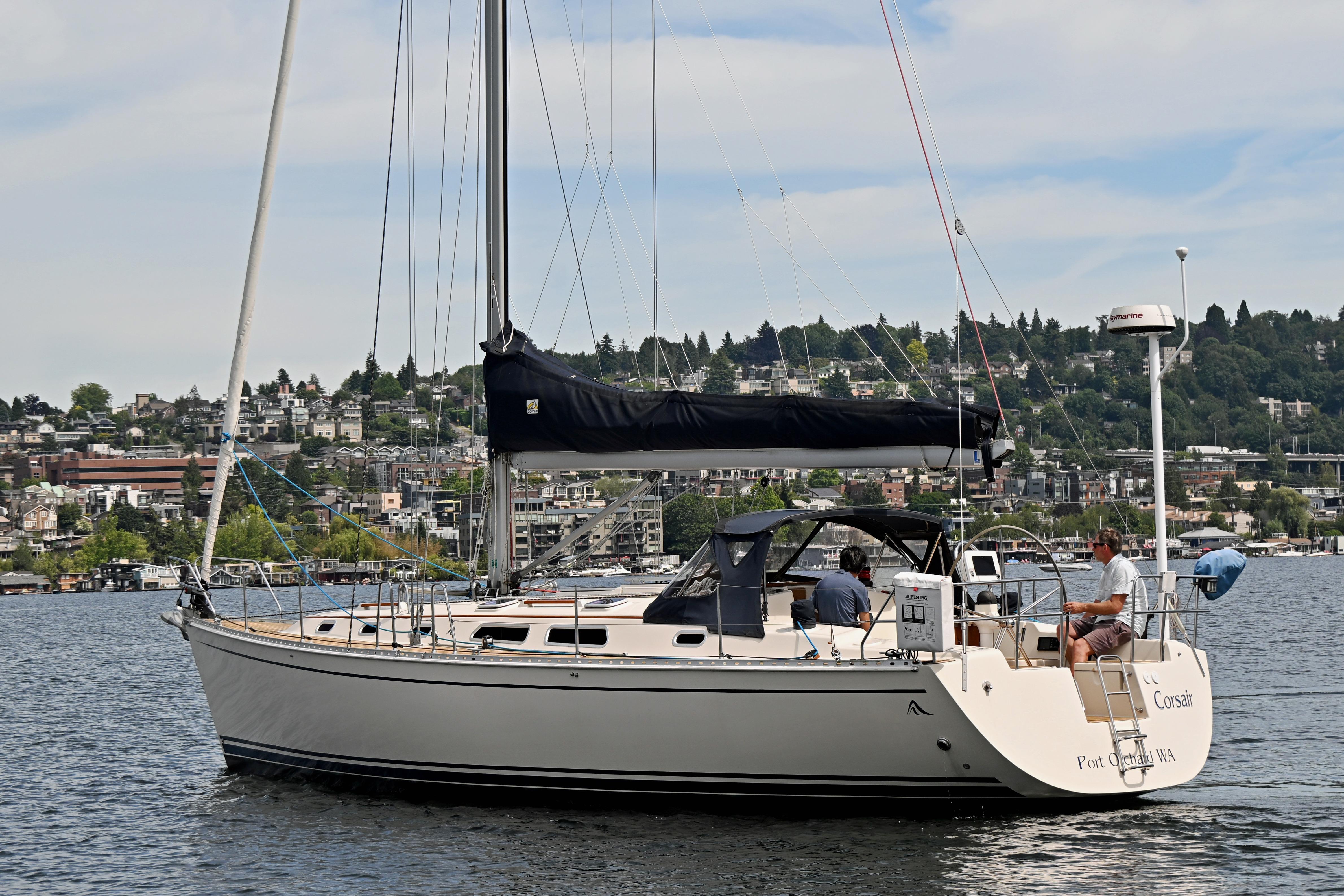 2004 Hanse 411 sailboat cruising on a scenic lake with cityscape background.