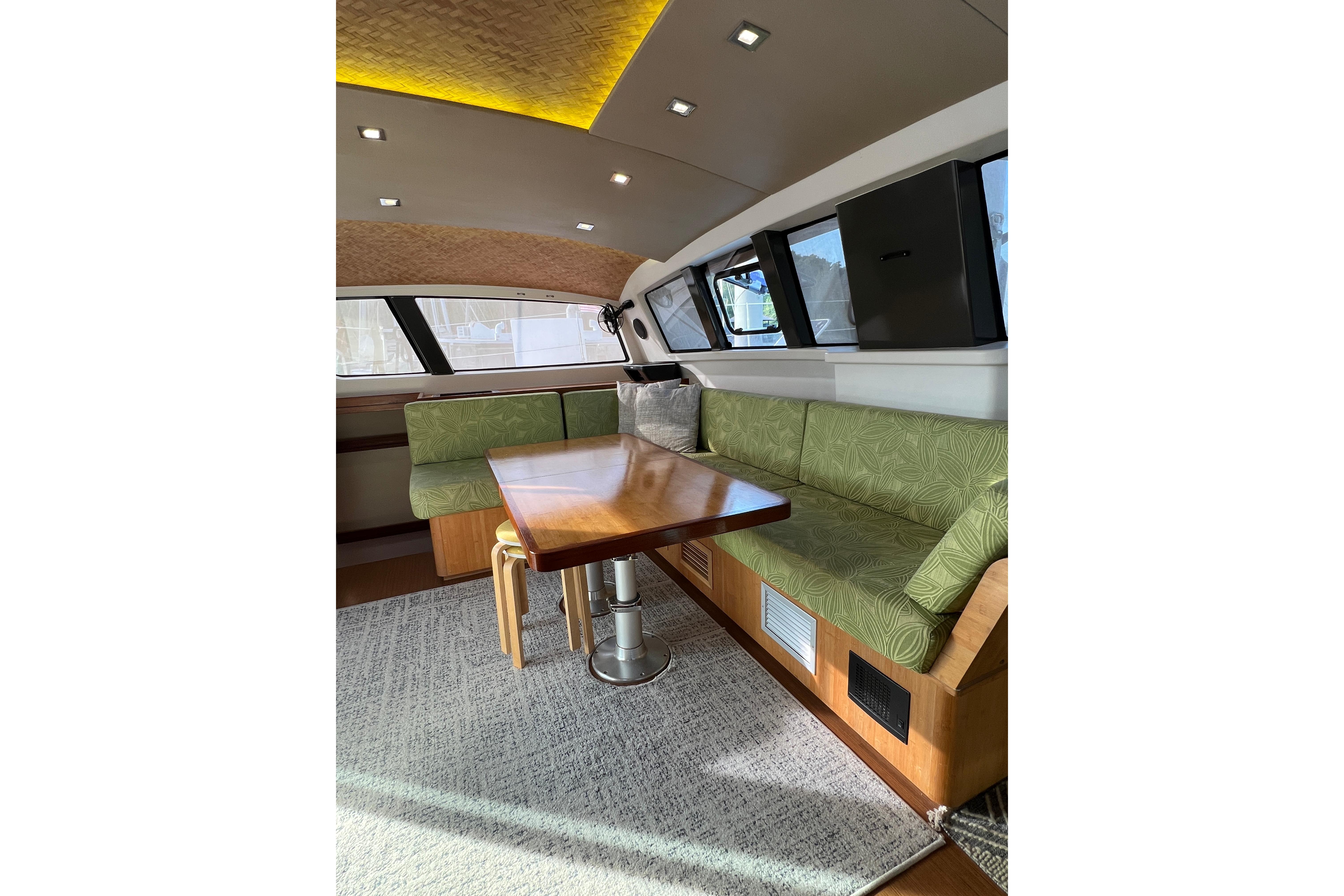 Luxurious interior of 2015 Outremer 51 catamaran with green seating and wooden table.