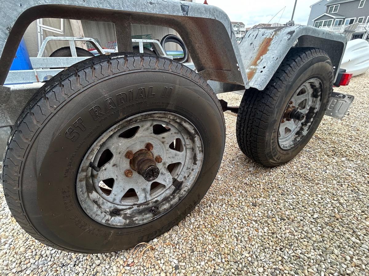 Trailer wheels for 1993 Grady-White 24 Explorer boat on gravel surface.