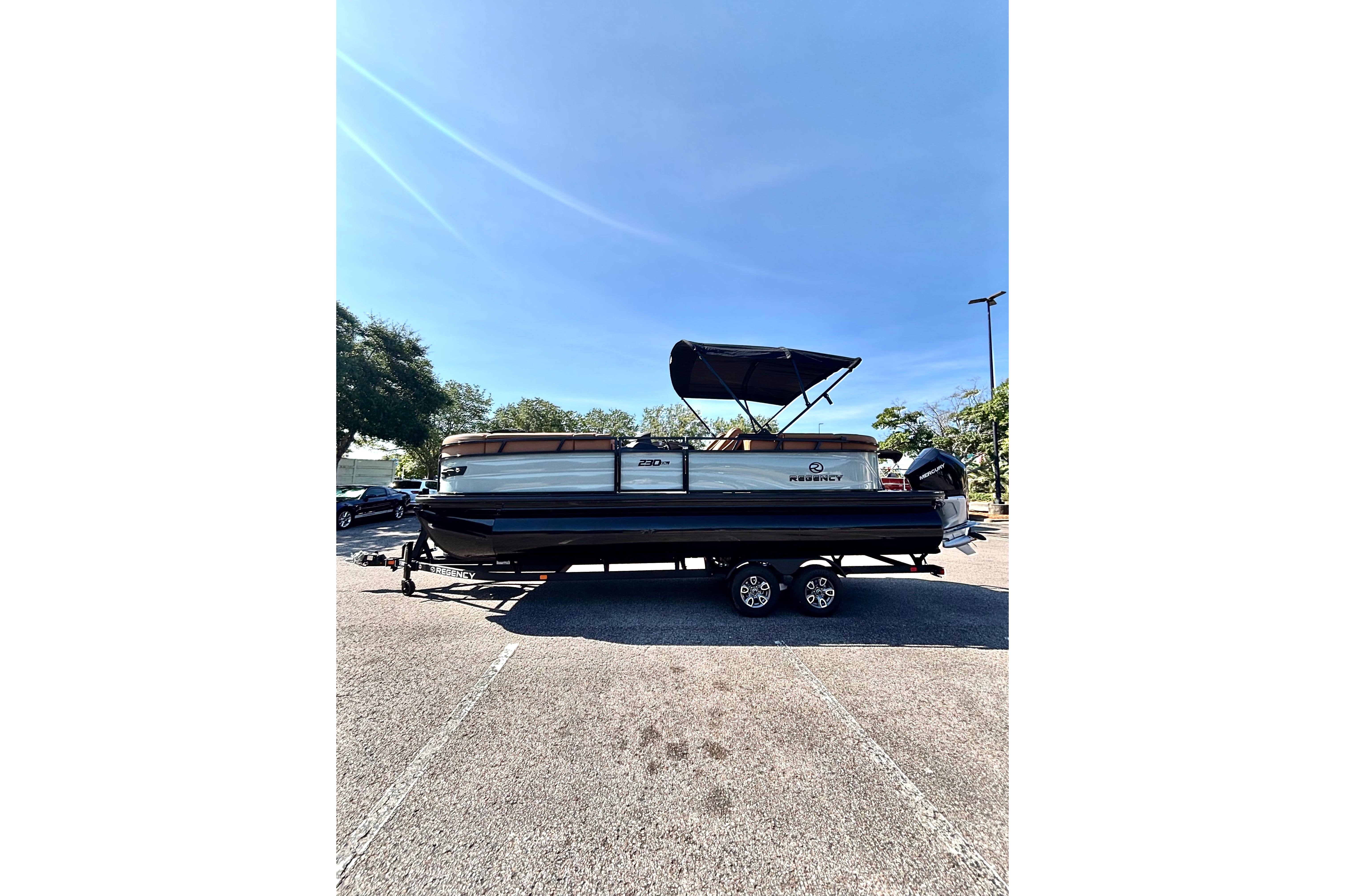 2026 Regency 230 DL pontoon boat on trailer under clear blue sky.