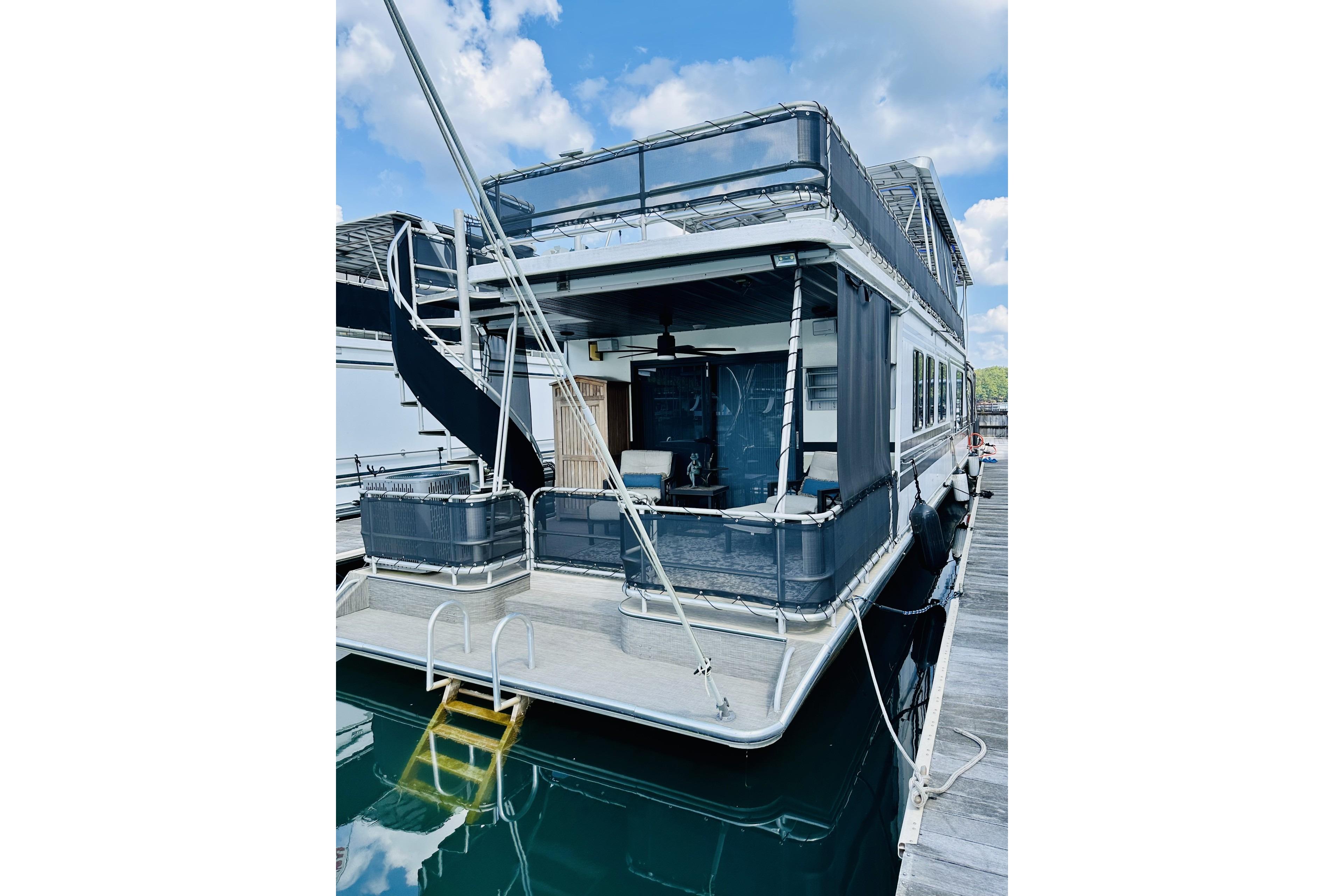 1992 Sumerset 66 houseboat docked, featuring a slide and spacious deck under a blue sky.