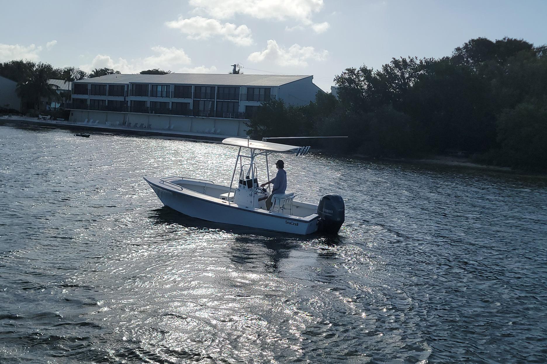 2008 SeaCraft SC 20 Classic boat cruising on a sunny day near a waterfront building.