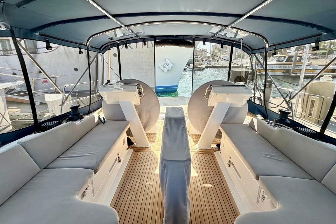 Spacious cockpit of 2016 Hanse 455 yacht with comfortable seating and marina view.