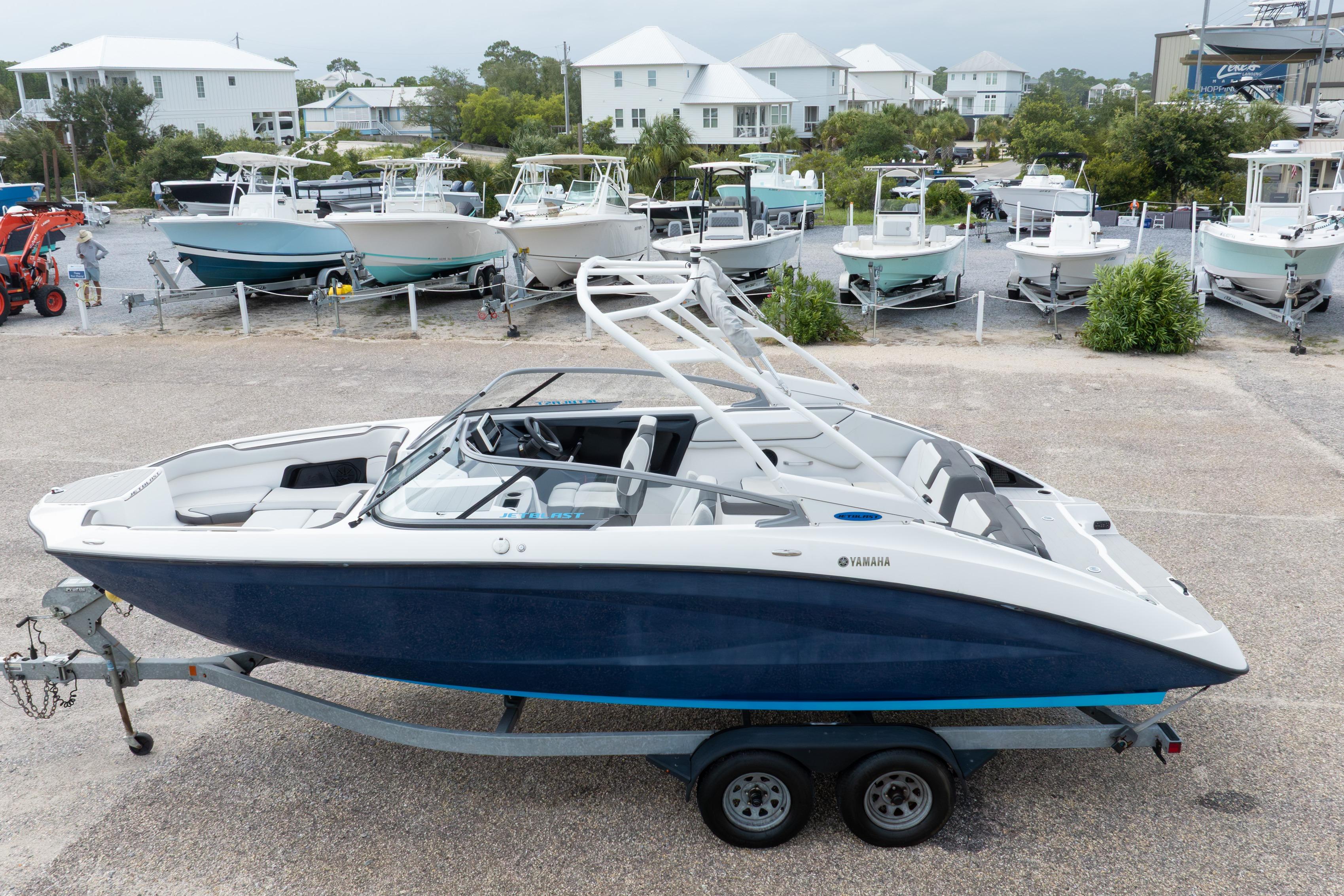 2021 Yamaha Boats AR250 on trailer, parked in marina with other boats in background.