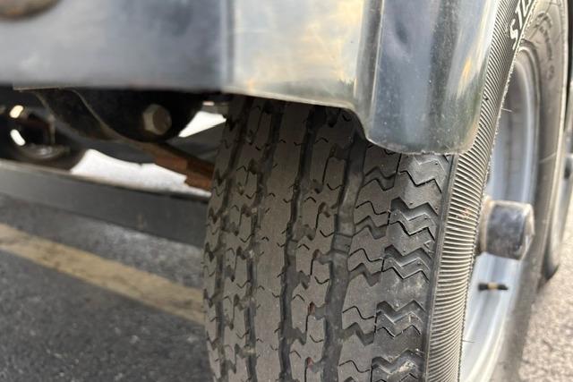 Close-up of a 2017 Searay SPX210 trailer tire on asphalt.