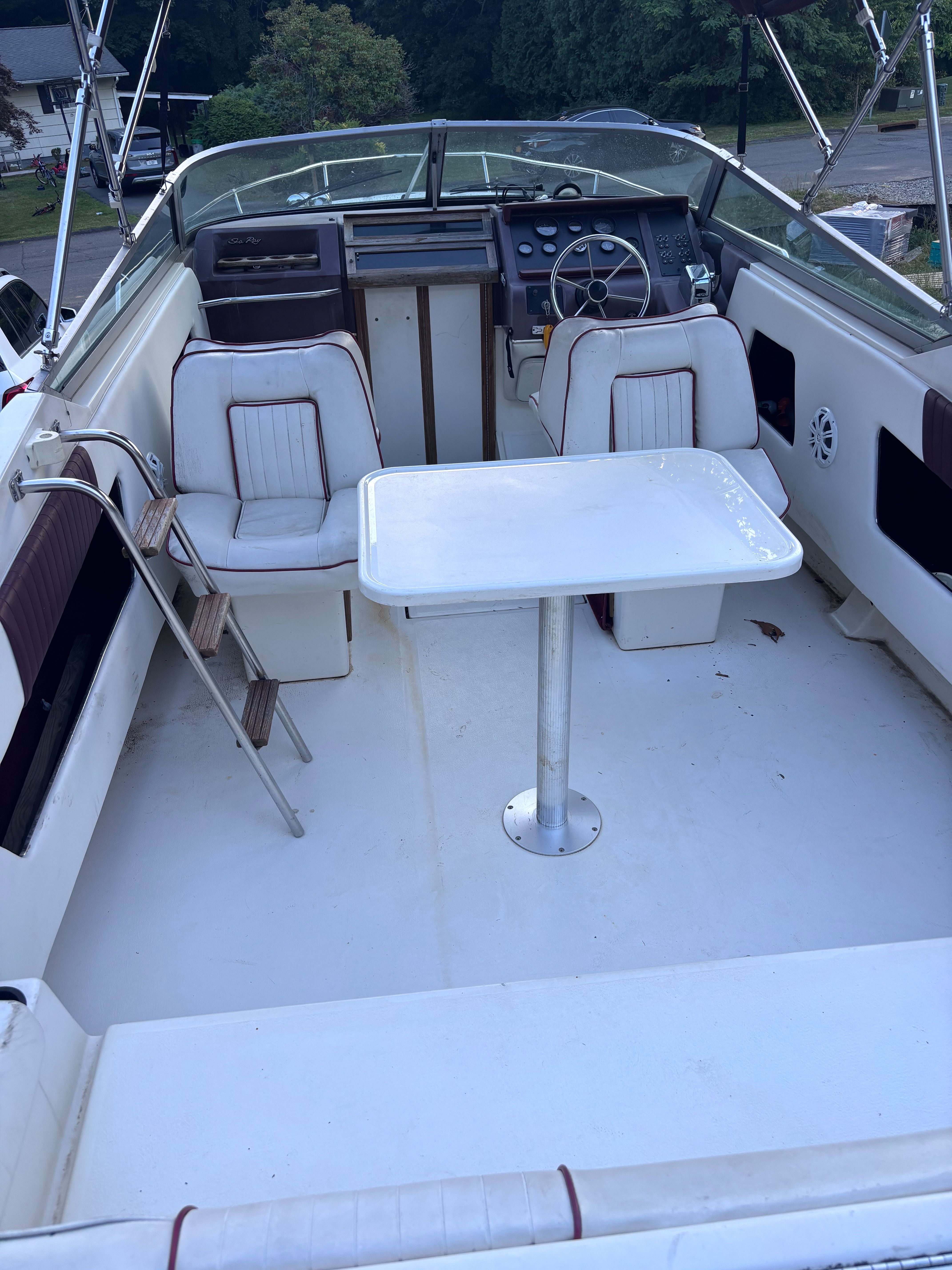 The image shows the cockpit of a 1989 Sea Ray Sundancer with white seats and a table.