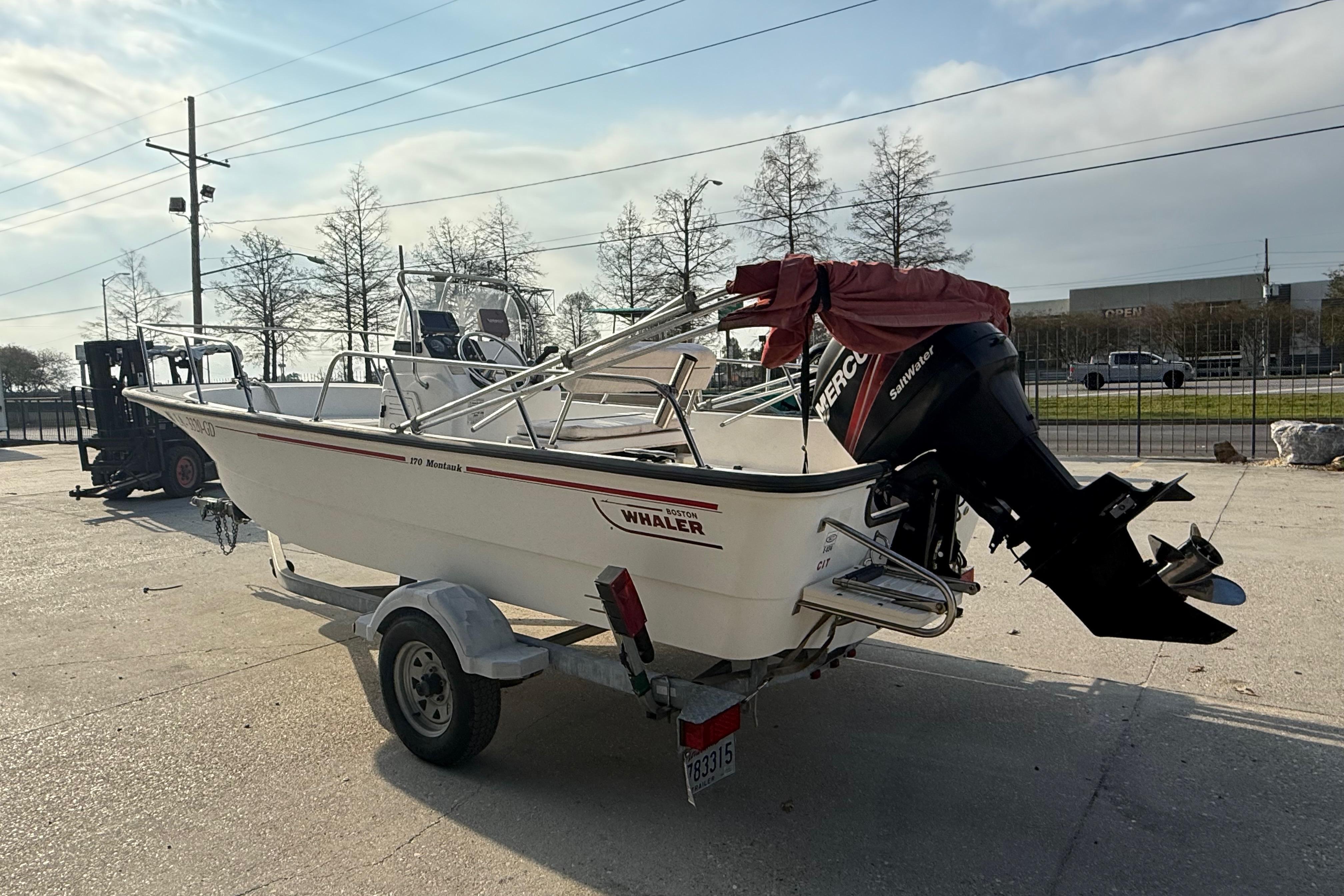 2005 Boston Whaler 17 Montauk boat on trailer with outboard motor in sunny outdoor setting.