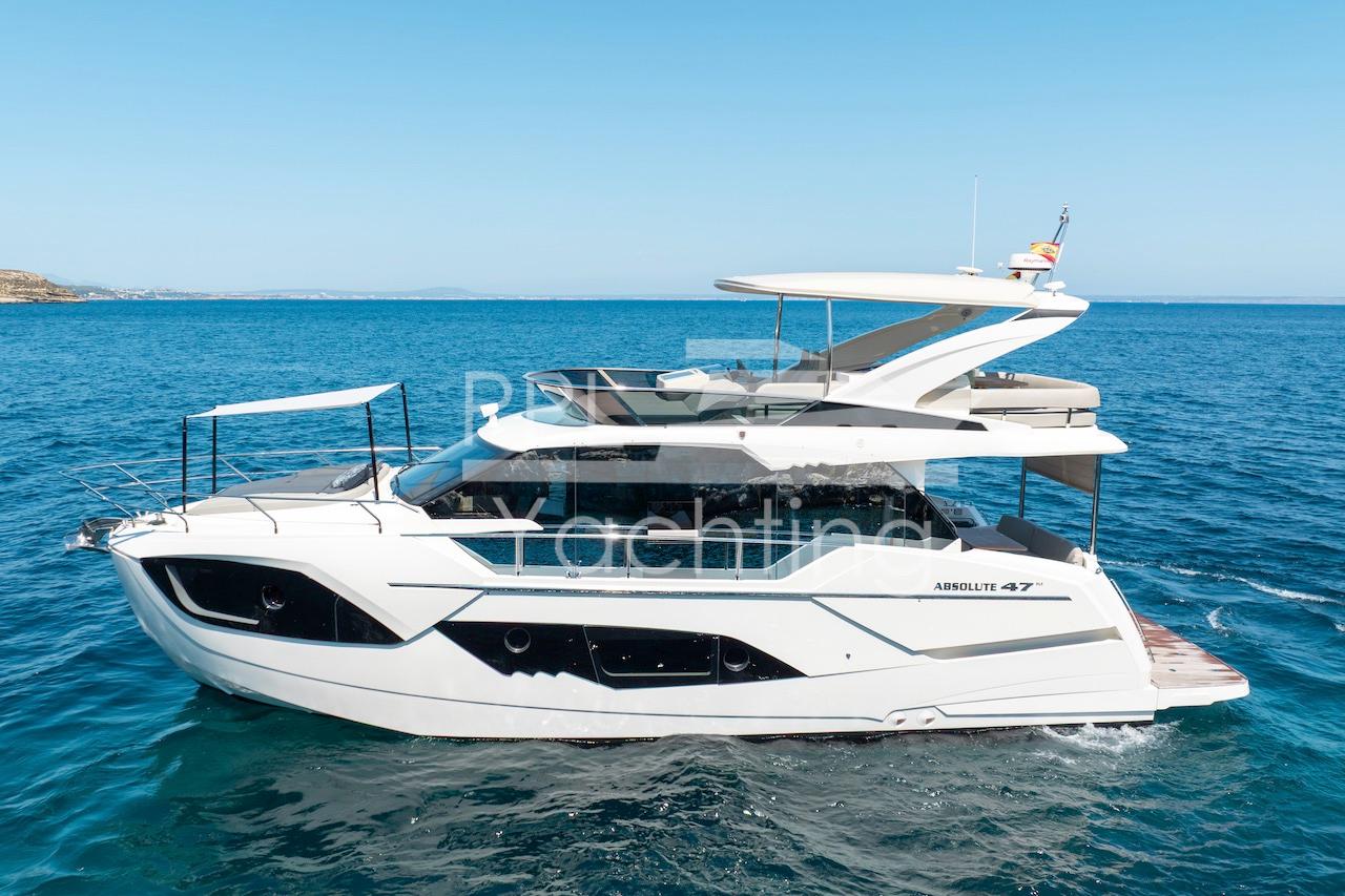 2021 Absolute 47 Fly yacht cruising on open sea under clear blue sky.
