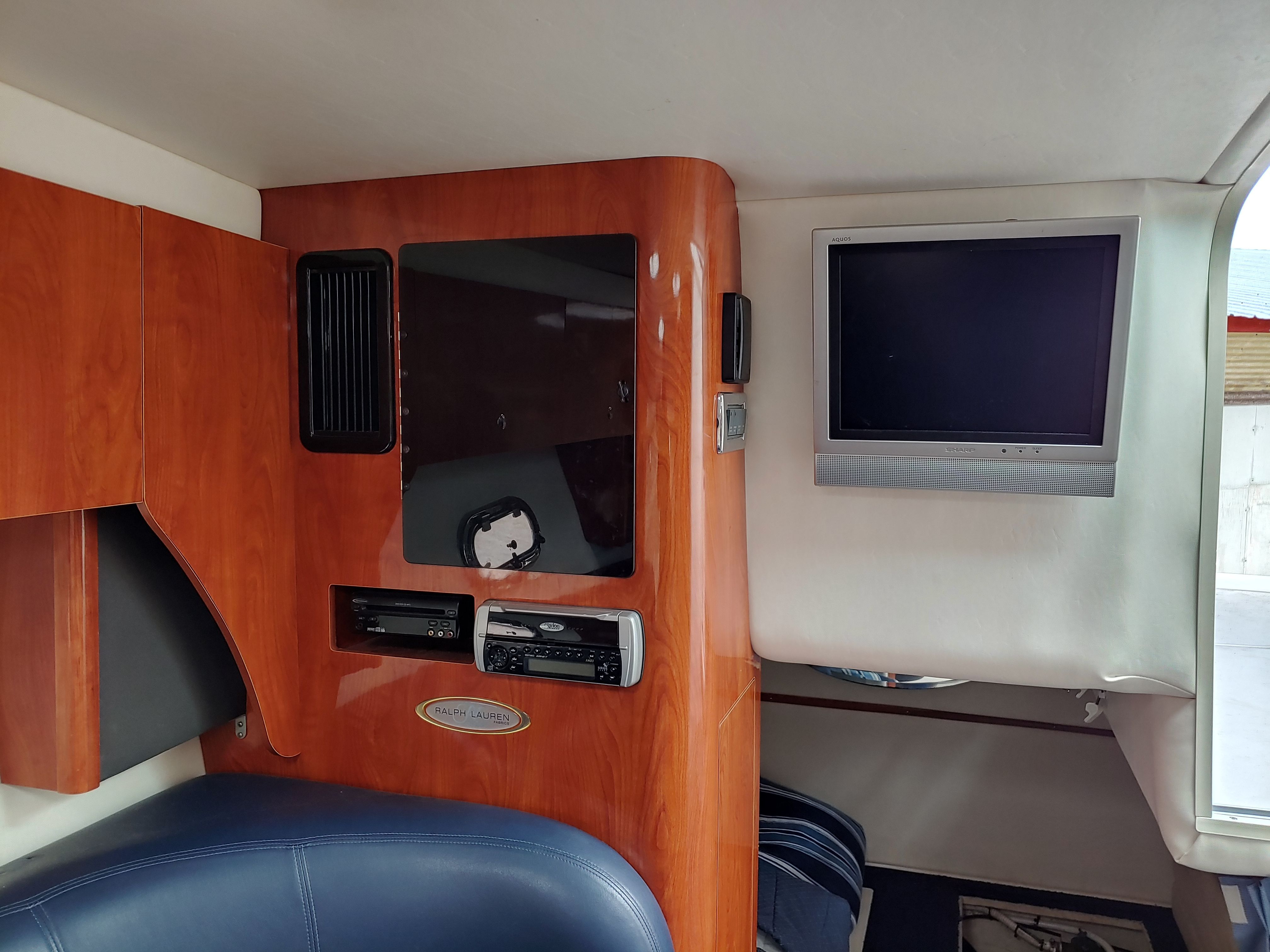 Interior of a yacht with wood paneling, a TV, and a stereo system.