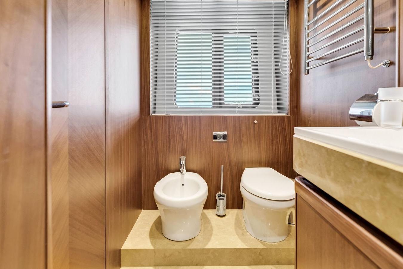 Luxurious yacht bathroom with wood paneling, featuring a toilet and bidet. Princess 85, 2012 model.