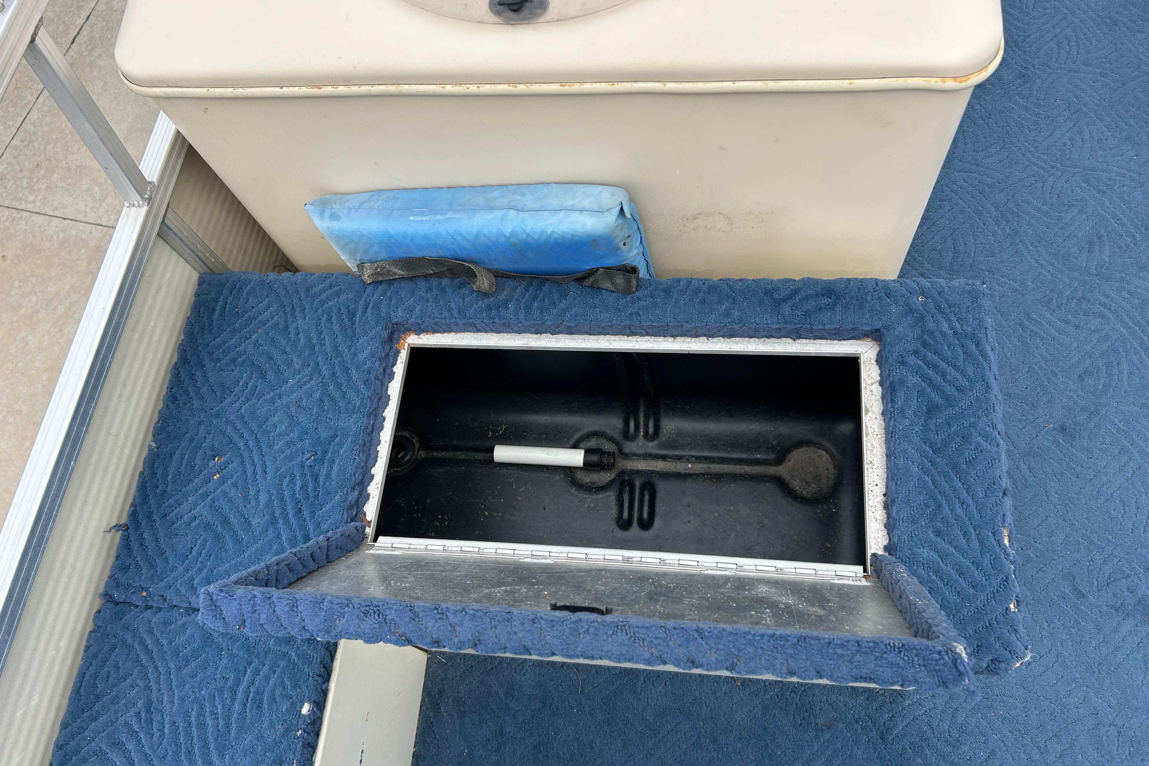 Open storage compartment on a 2002 Lowe Trinidad 200 boat with blue carpet.