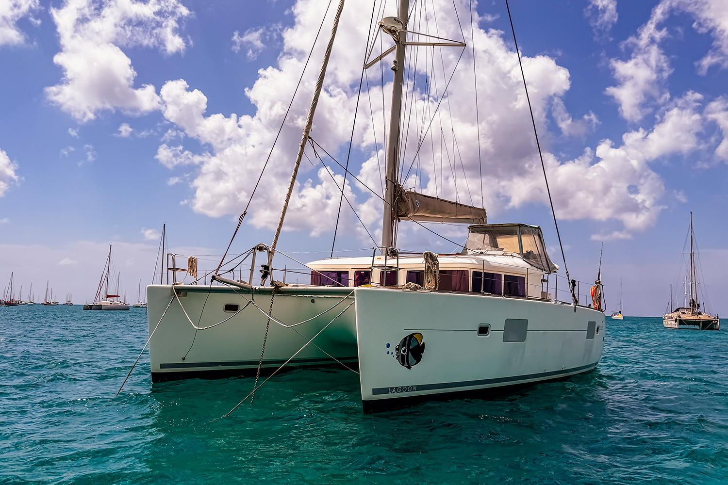 2010 Lagoon 400 catamaran sailing on clear blue waters under a partly cloudy sky.