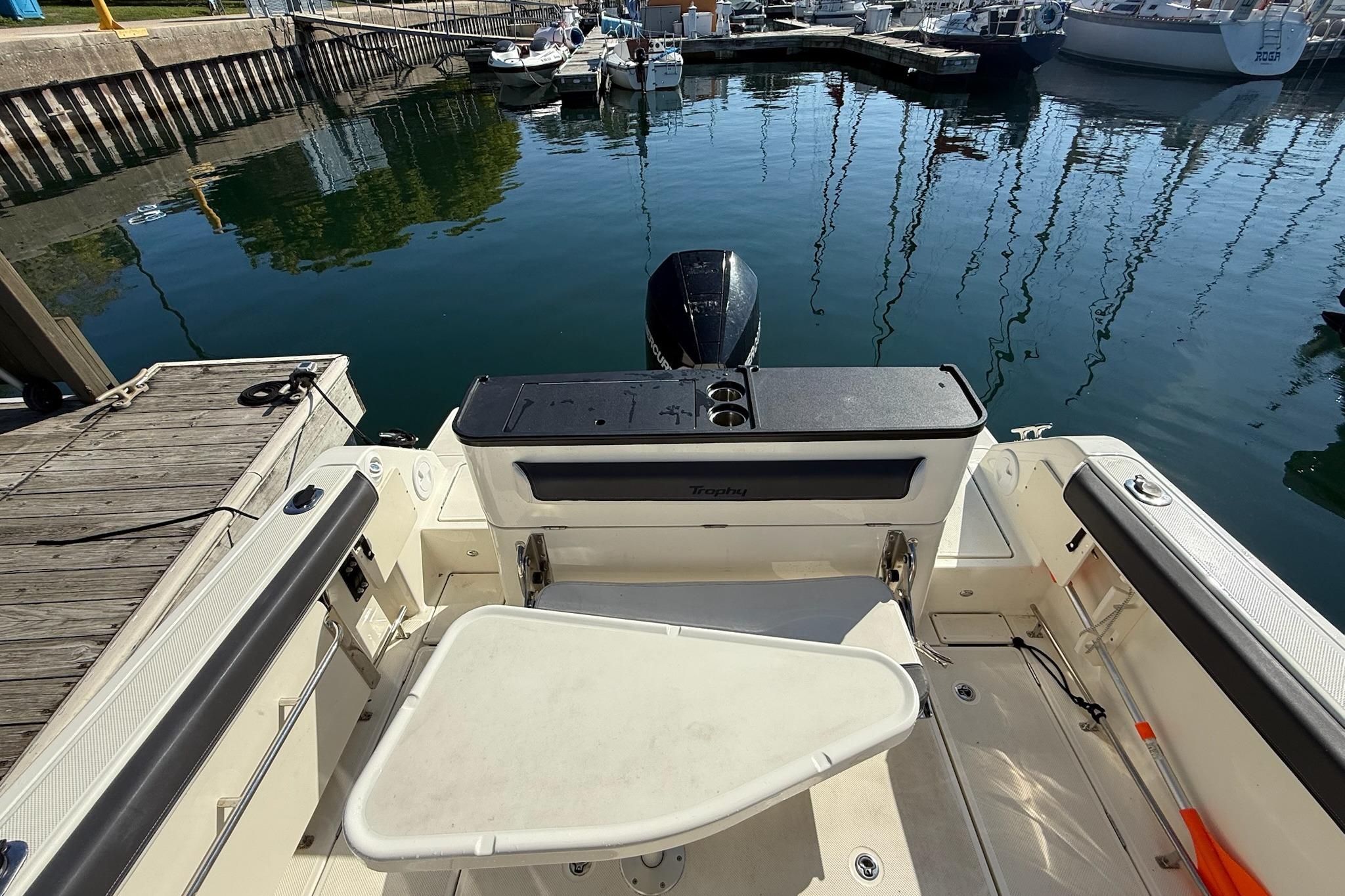 2024 Bayliner Trophy T25 Pilothouse at dock, showcasing spacious deck and seating area.