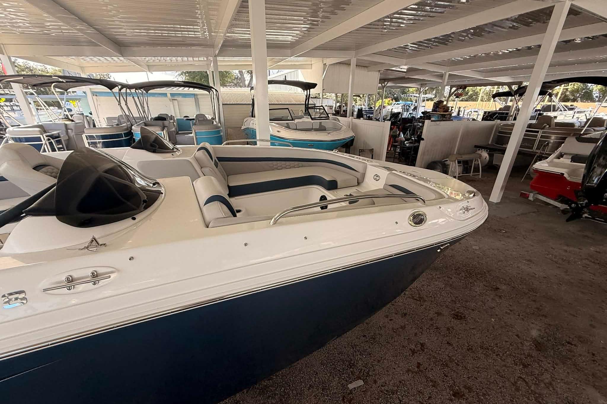2026 Hurricane Sundeck Sport 218 OB boat in covered storage, showcasing sleek design.