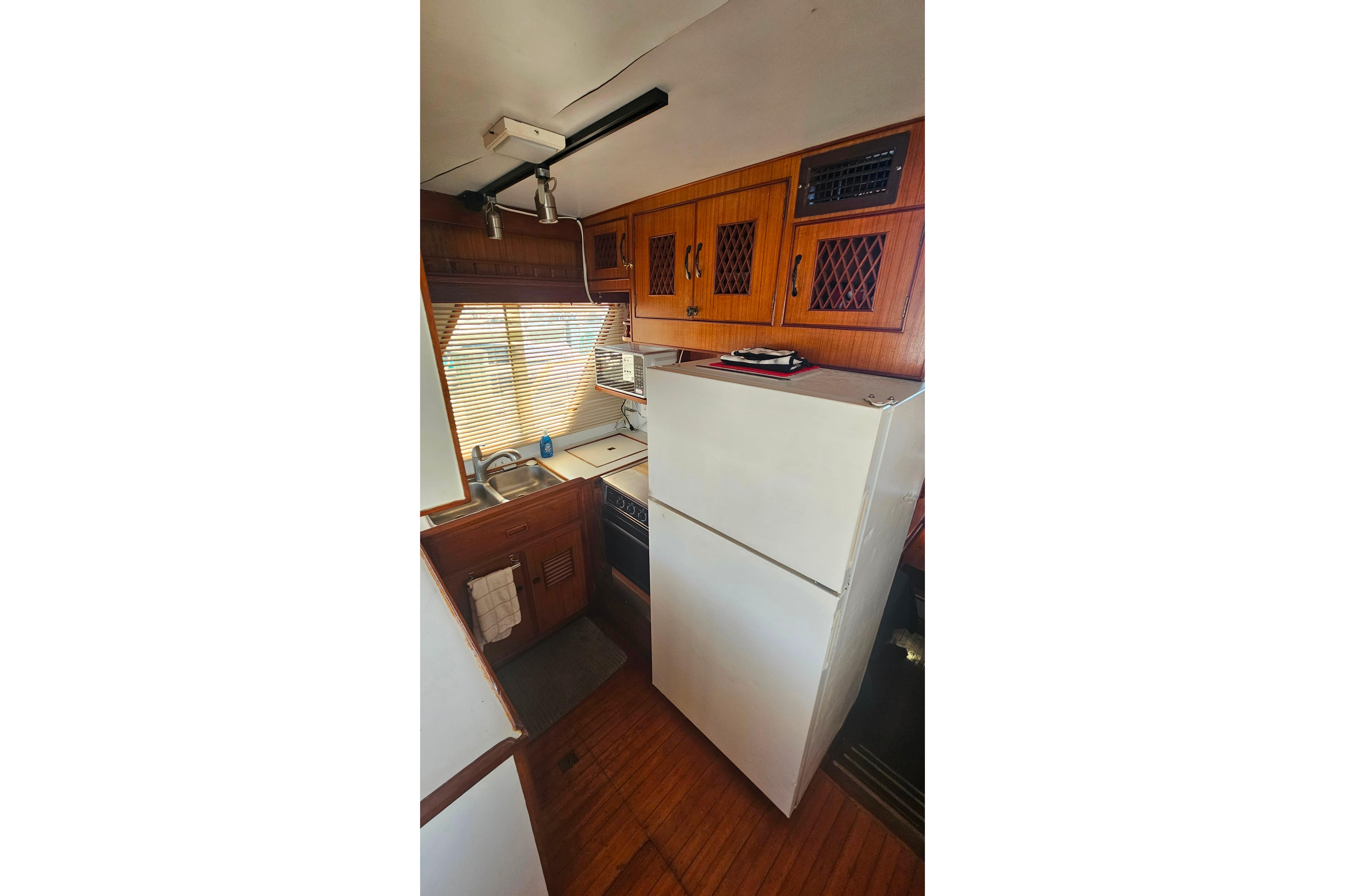 Compact kitchen in 1981 Sea Ranger 47 Pilothouse with wooden cabinets and appliances.