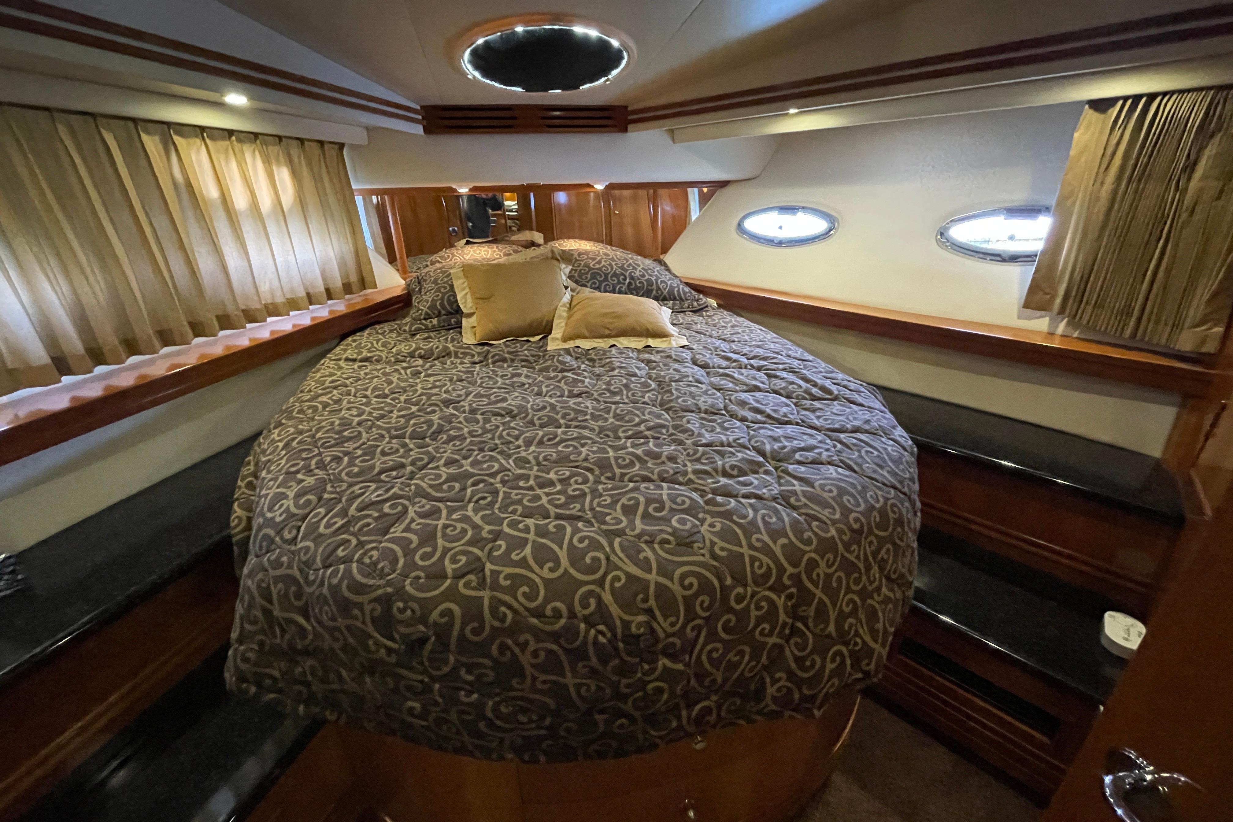 Luxurious bedroom interior of 2002 Carver 570 Voyager Pilothouse yacht with elegant bedding.