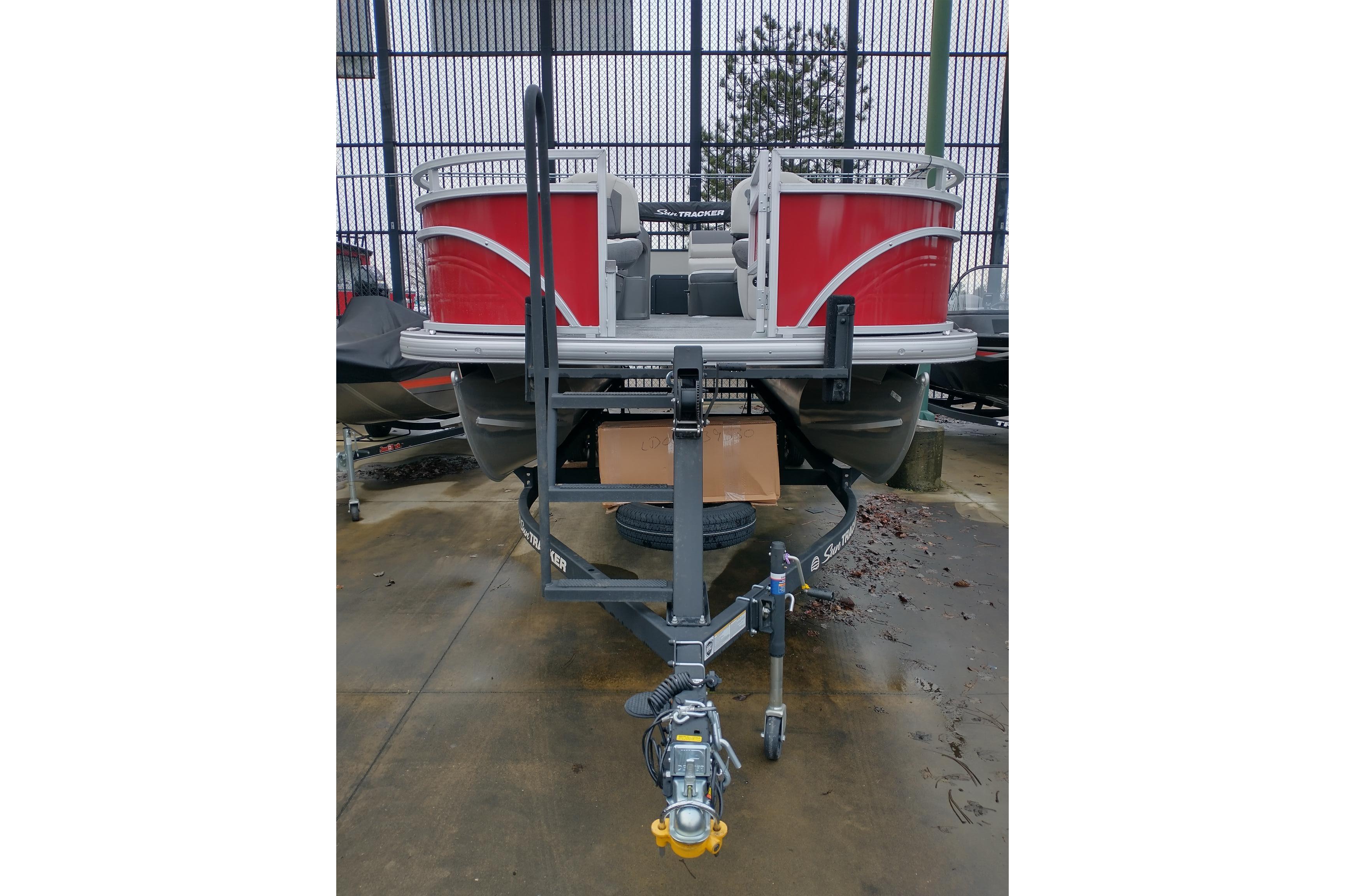 2026 Sun Tracker Fishin' Barge 22 DLX pontoon boat on trailer, front view.