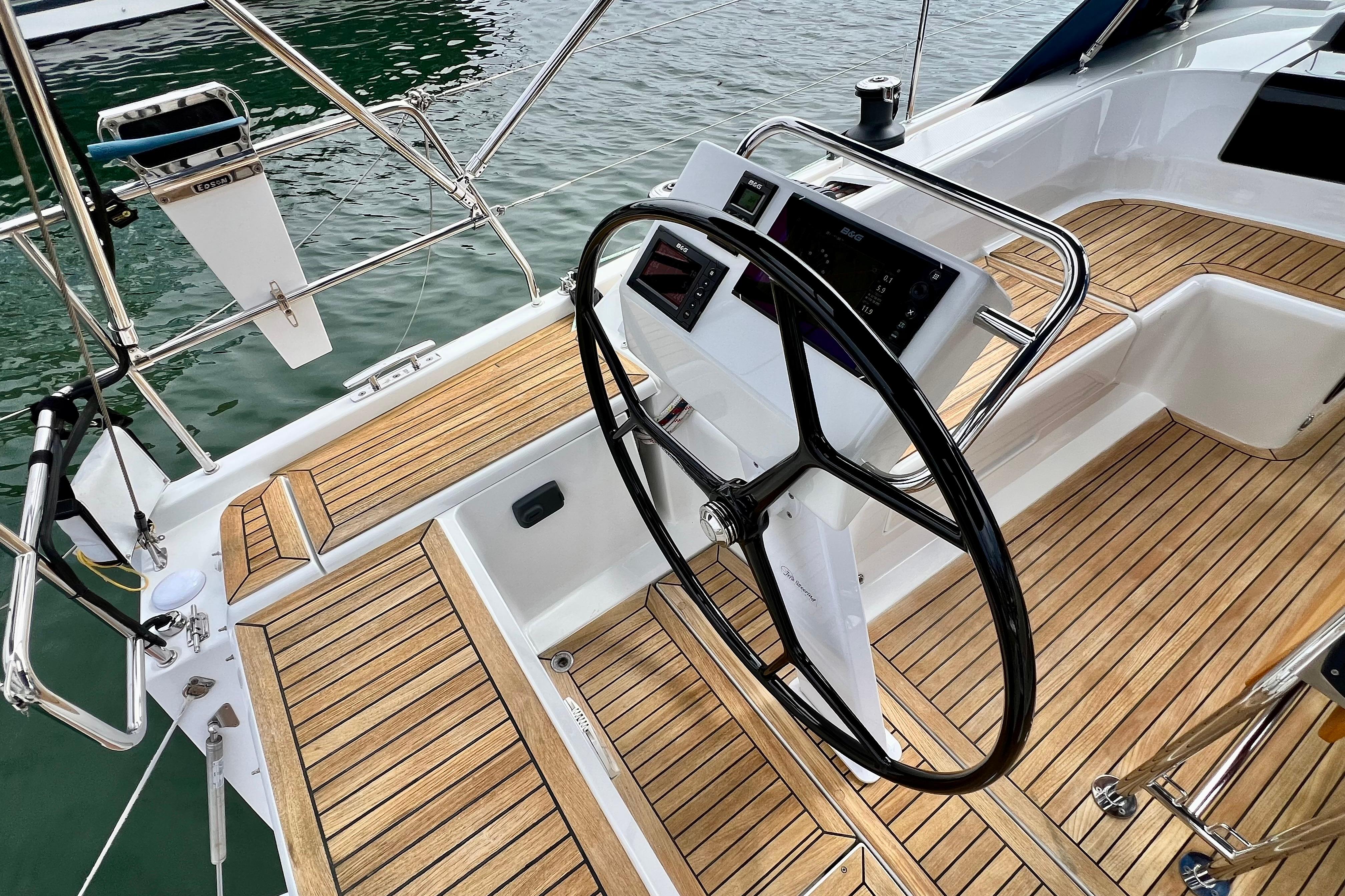 Steering wheel and cockpit of 2016 Hanse 455 yacht with teak flooring.
