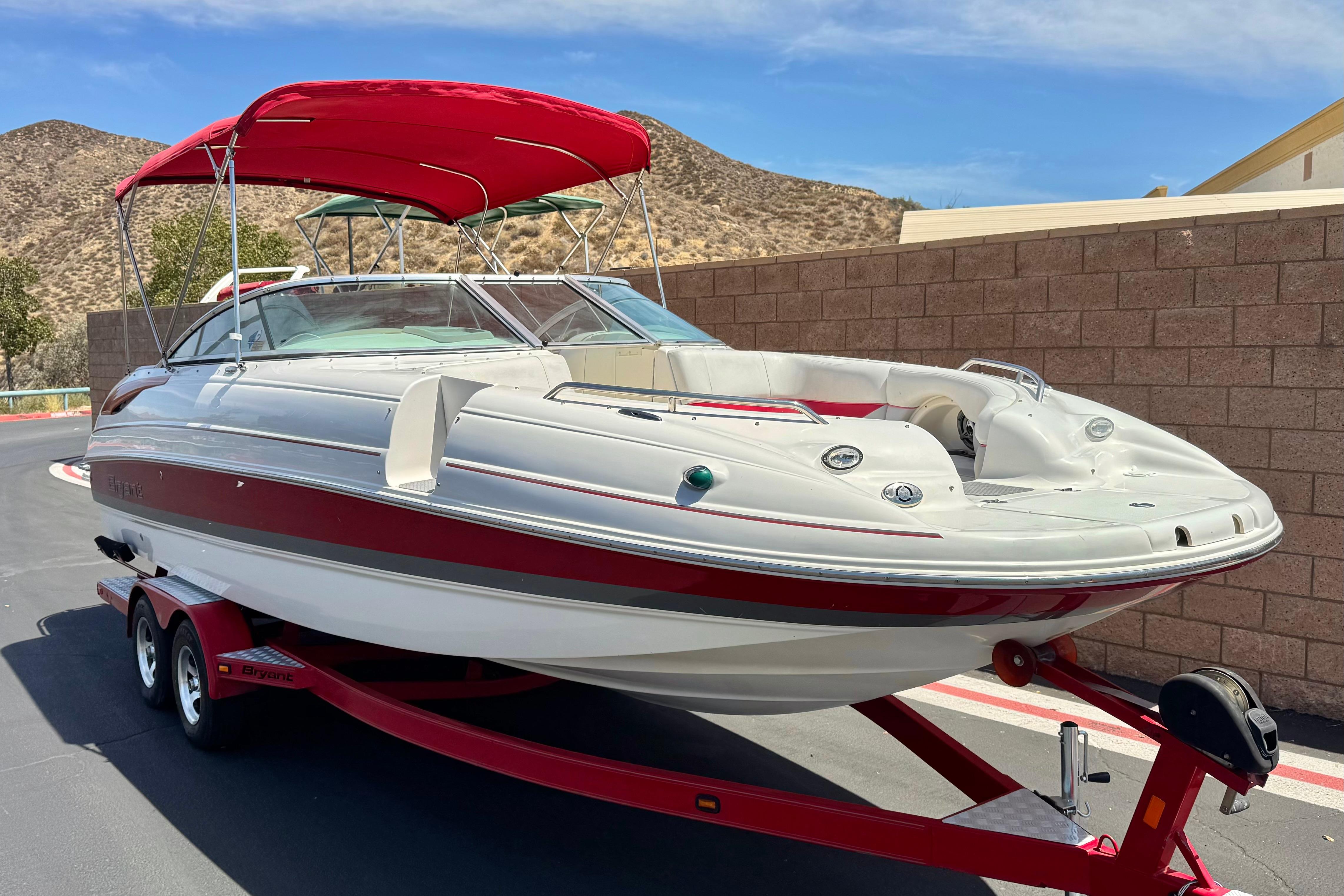 2010 Bryant 255 boat with red canopy on trailer, parked near brick wall.