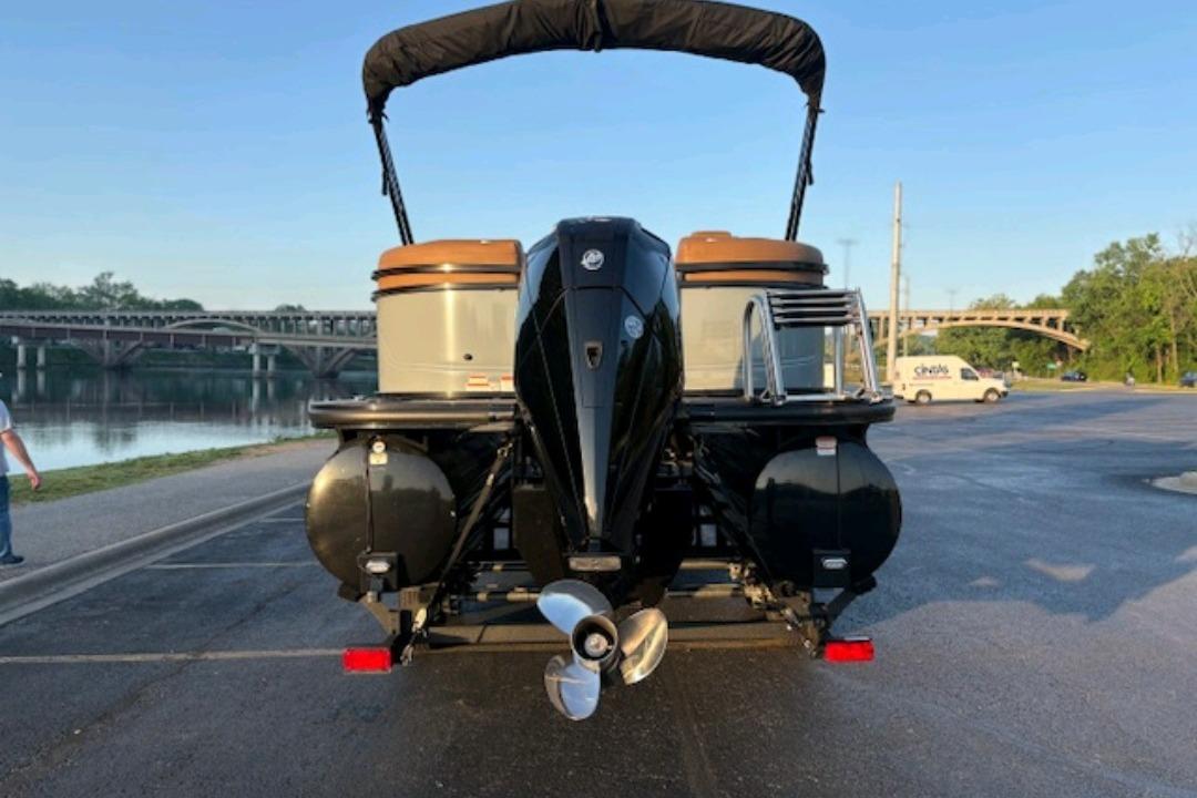 2026 Regency 230 DL pontoon boat parked near a scenic river and bridge.