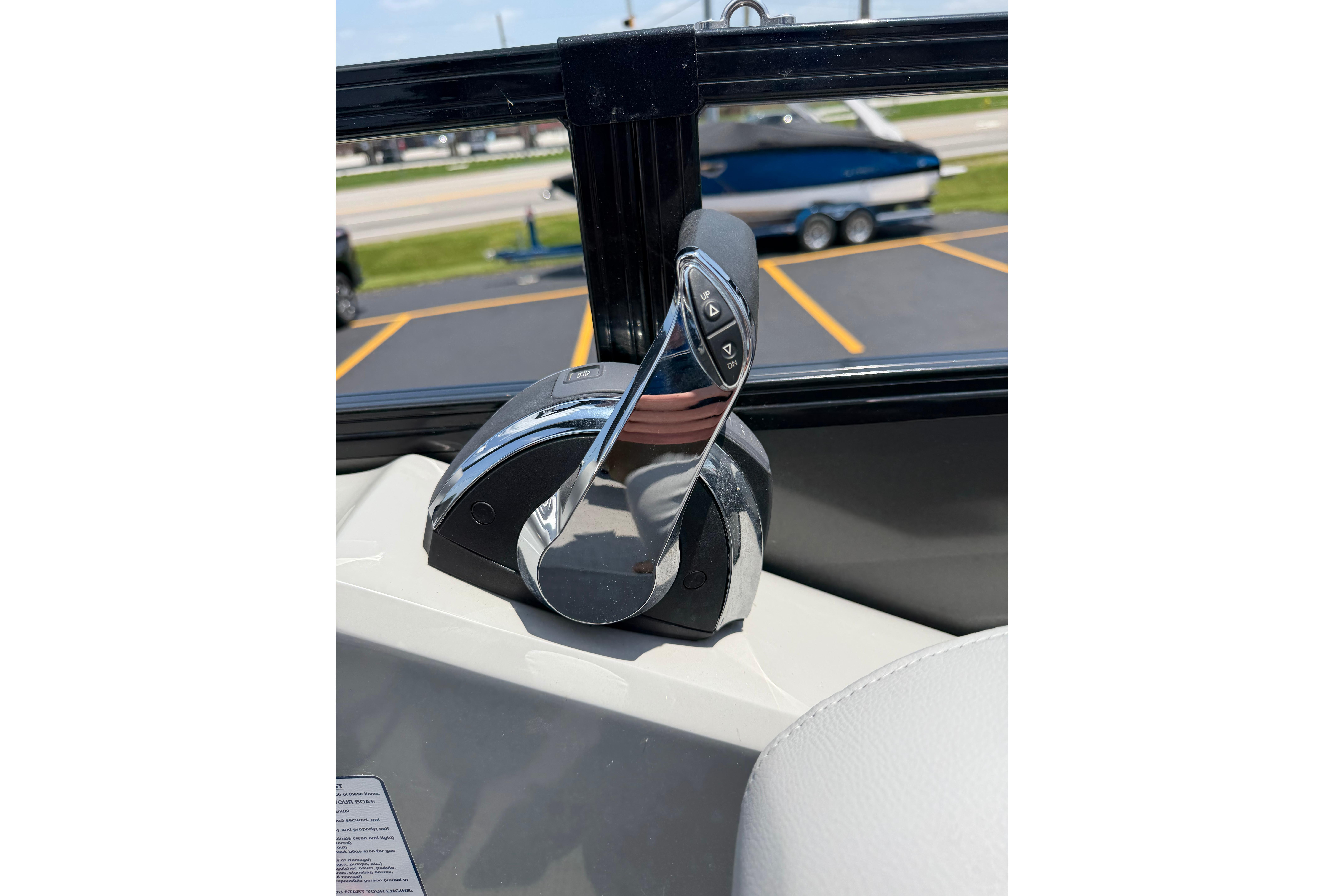 Throttle control of 2019 Regency 230 DL3 boat, with parking lot and boat in background.