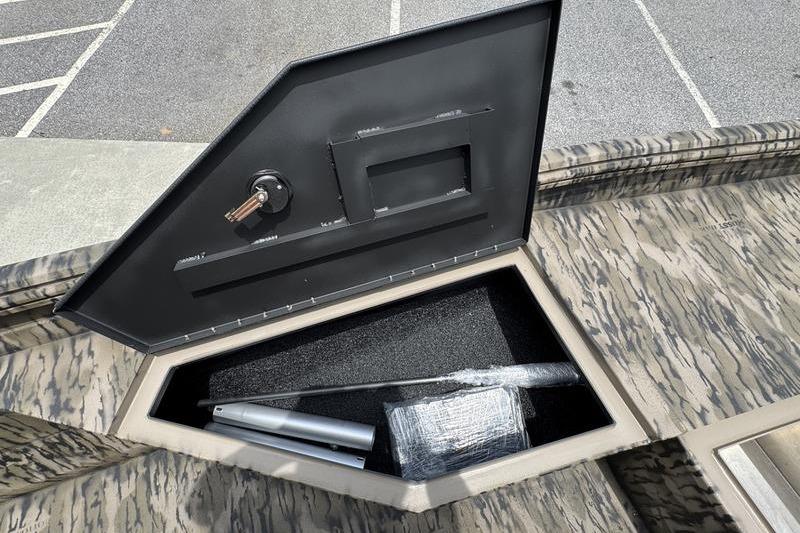 Open storage compartment on 2027 Excel 230 Bay Pro Elite boat, showing interior contents.