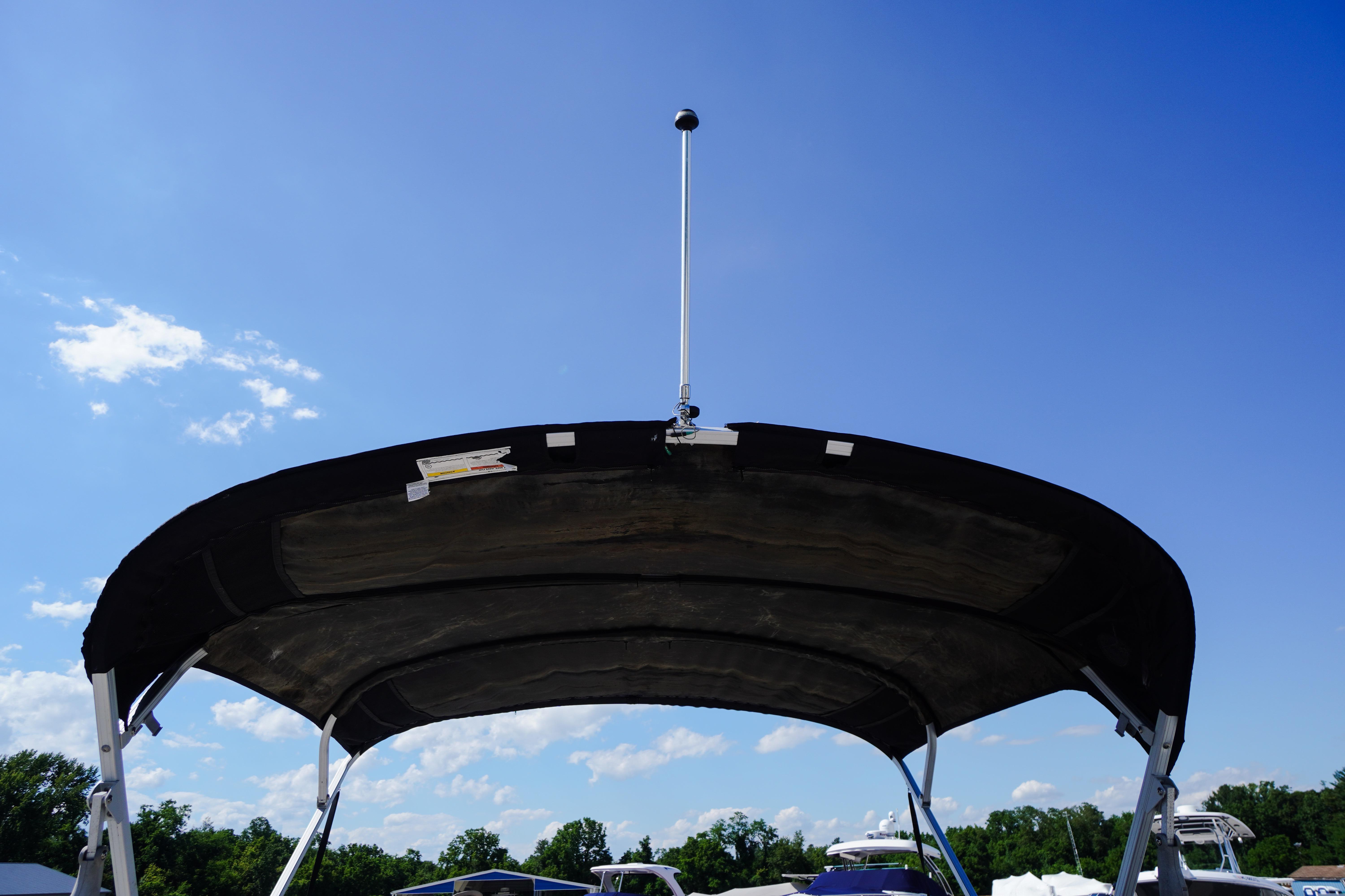 2019 SUNTRACKER Fishin' Barge 22 DLX canopy against clear blue sky.