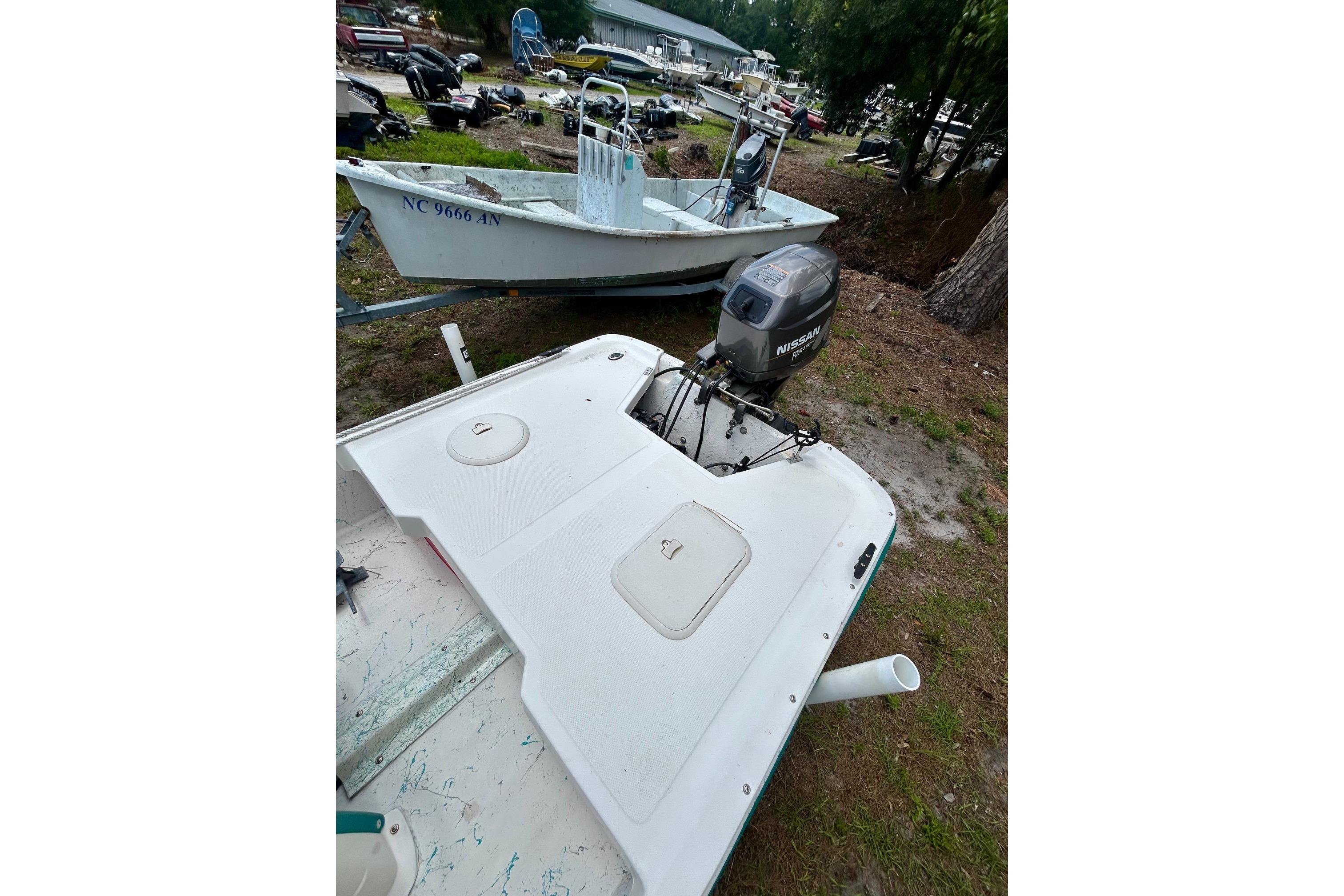 2002 Sundance K16CC boat with Nissan outboard motor in a yard setting.