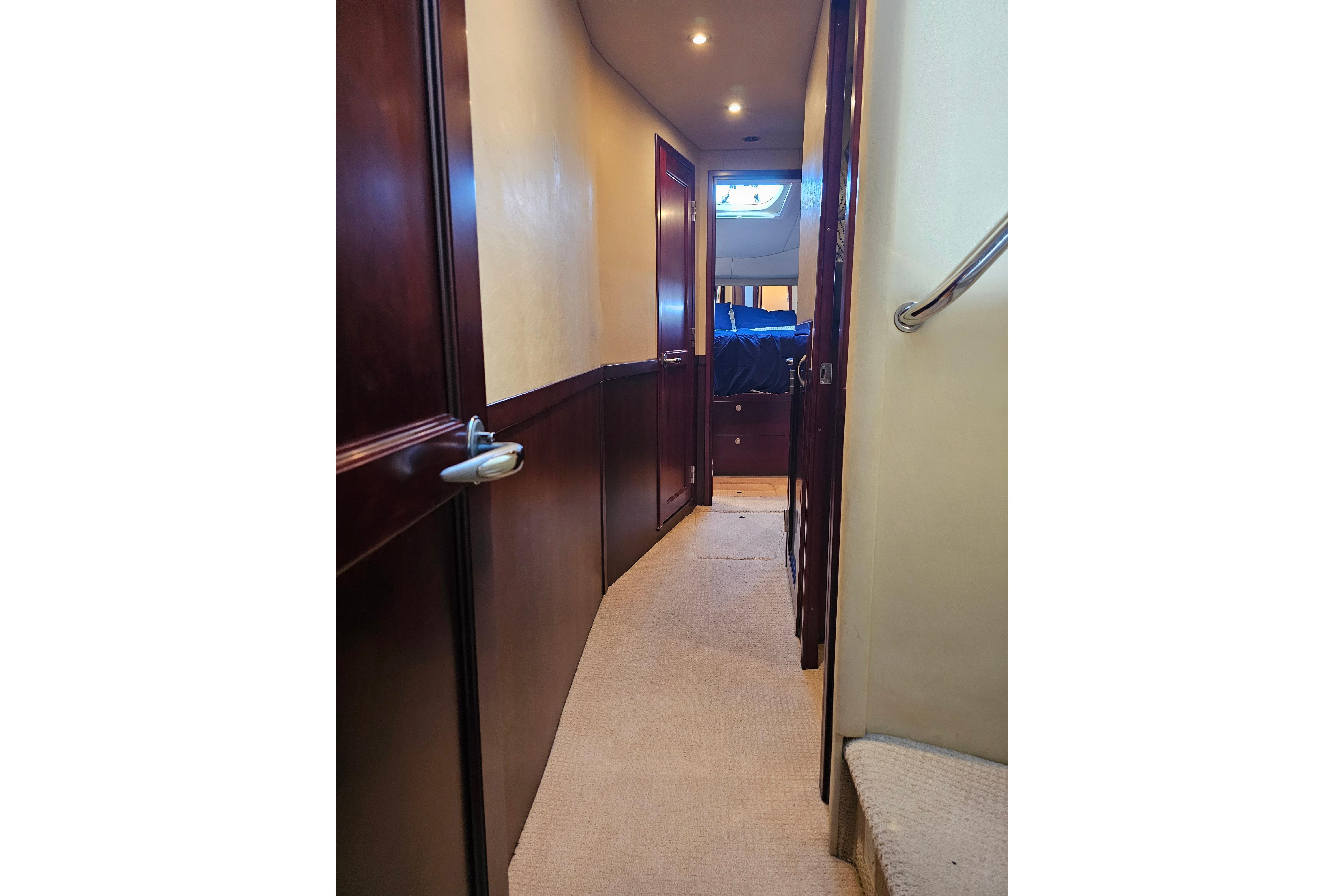 Hallway inside 2006 Sea Ray 580 Sedan Bridge yacht, featuring wooden doors and carpeted flooring.