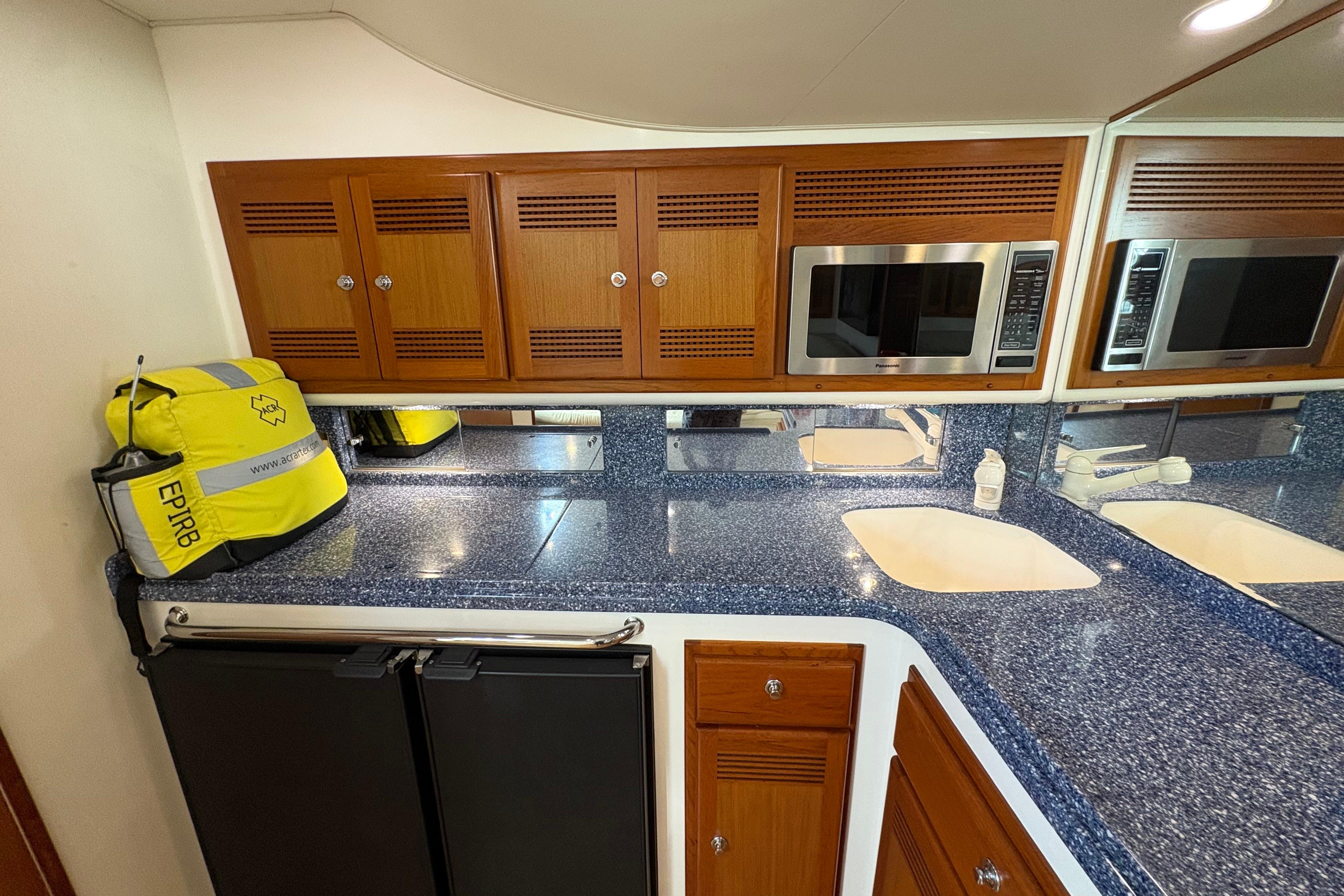 2004 Cabo 40 Hardtop Express yacht kitchen with blue countertops, wooden cabinets, and microwave.