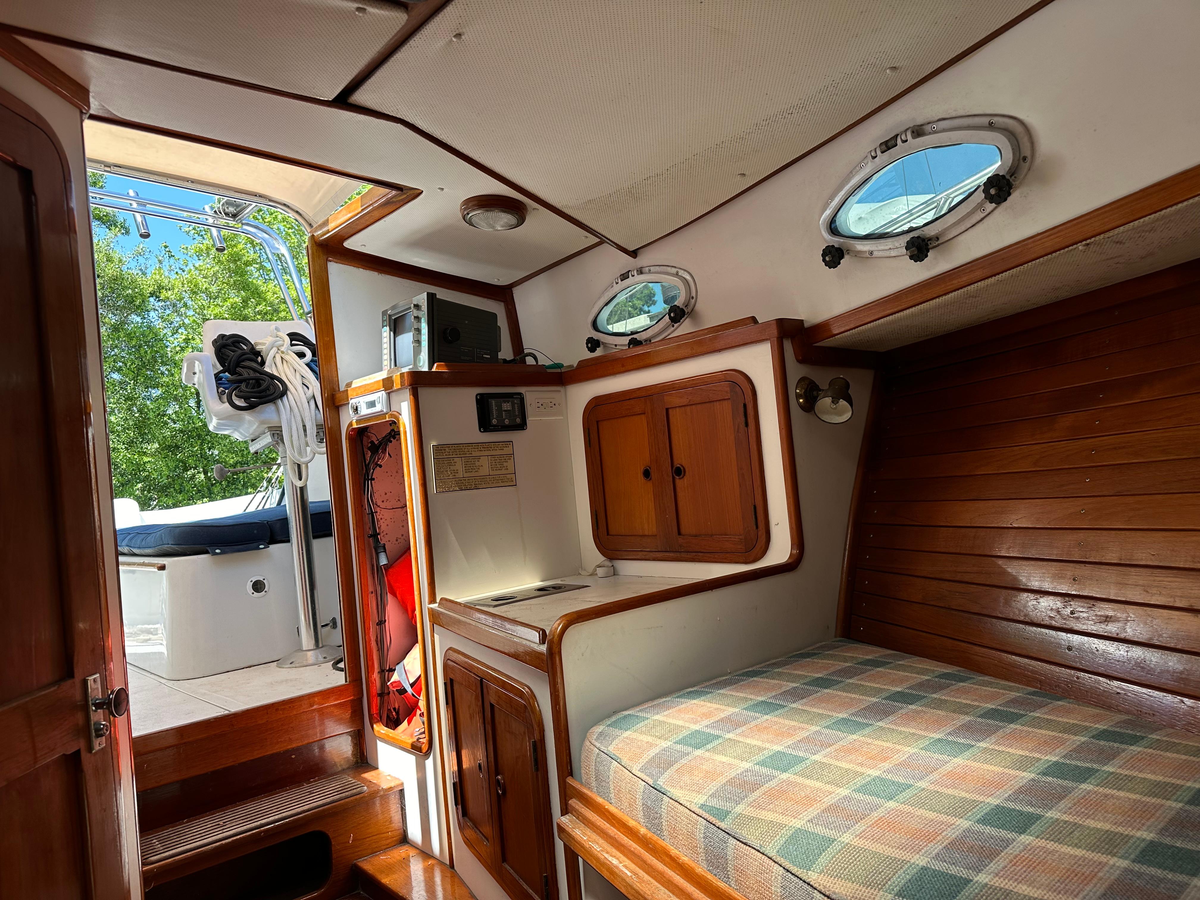 Interior of 1988 Black Watch 30 EXPRESS boat with wooden cabinetry and plaid bedding.