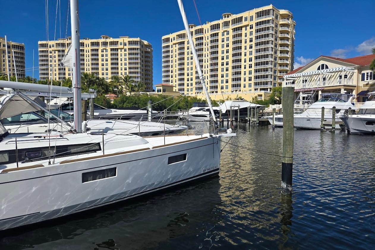 2023 Beneteau Oceanis 38.1 yacht docked in marina with tall buildings in background.