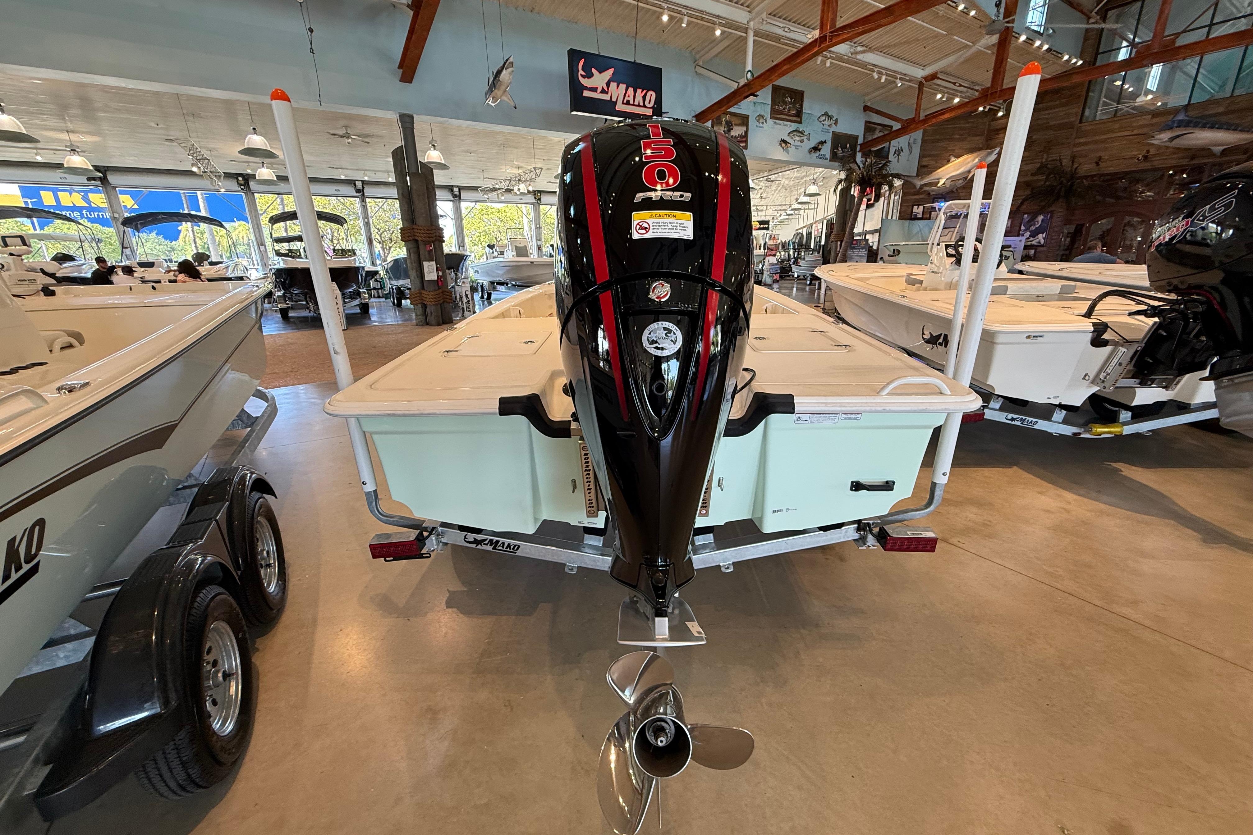 2026 Mako 18 Pro Skiff boat displayed in a showroom with powerful outboard motor.