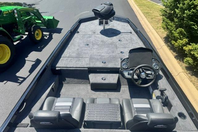 2026 Ranger RT198P boat interior with seating and steering console, parked near green tractor.