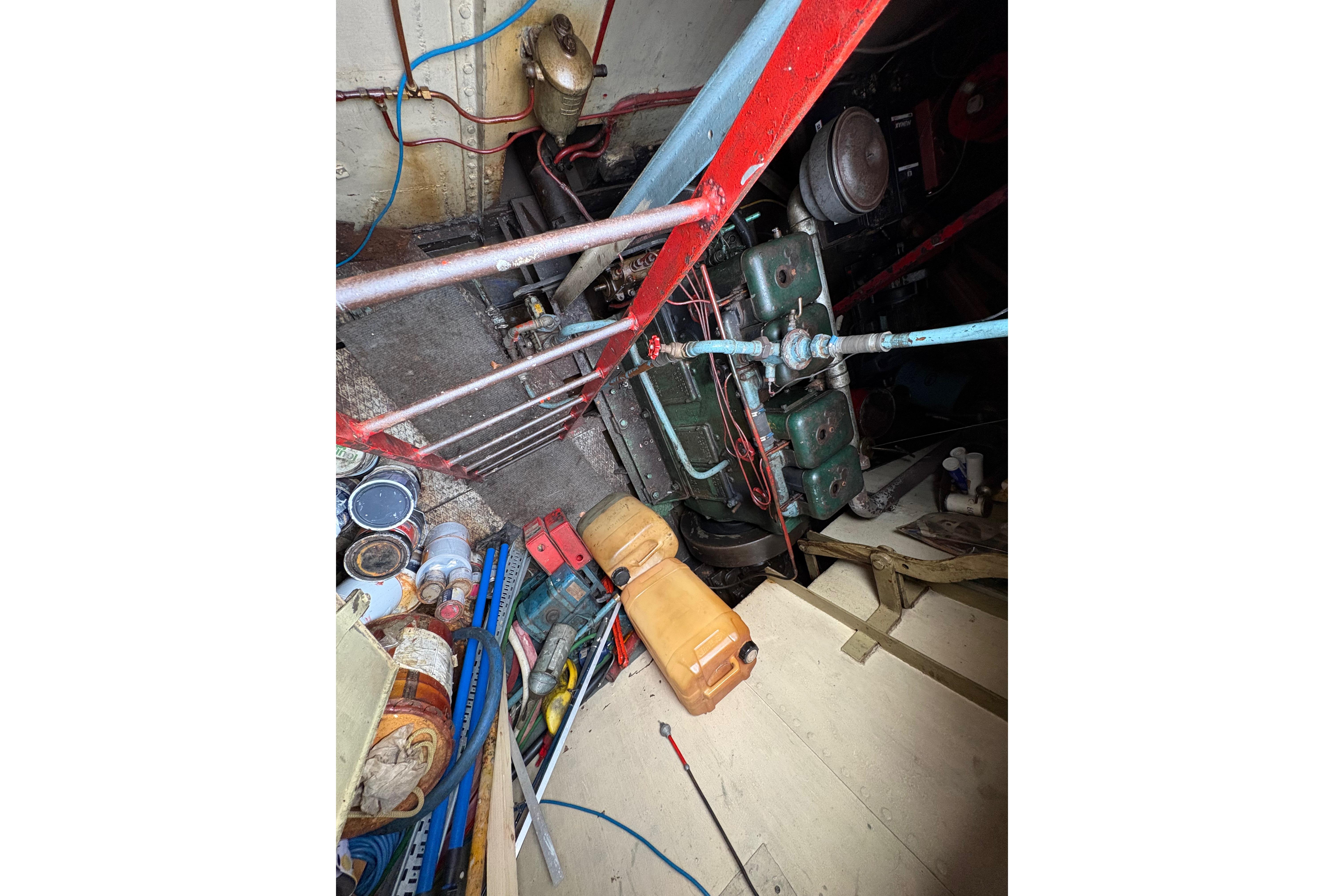 Engine room of a 1910 Dutch Barge Klipper with tools and equipment scattered around.
