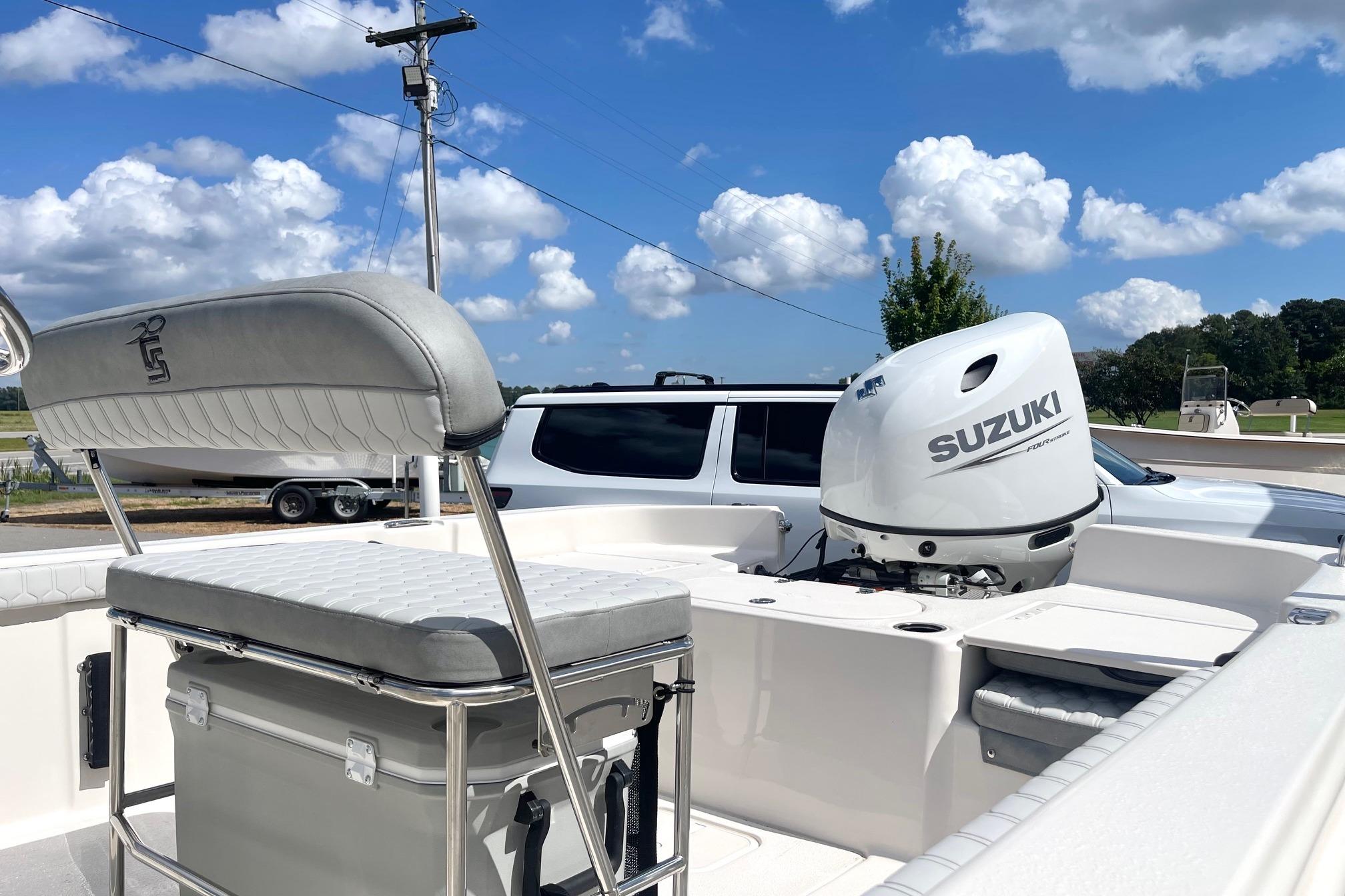 2026 Carolina Skiff 19 LS boat with Suzuki outboard motor, parked under a clear blue sky.