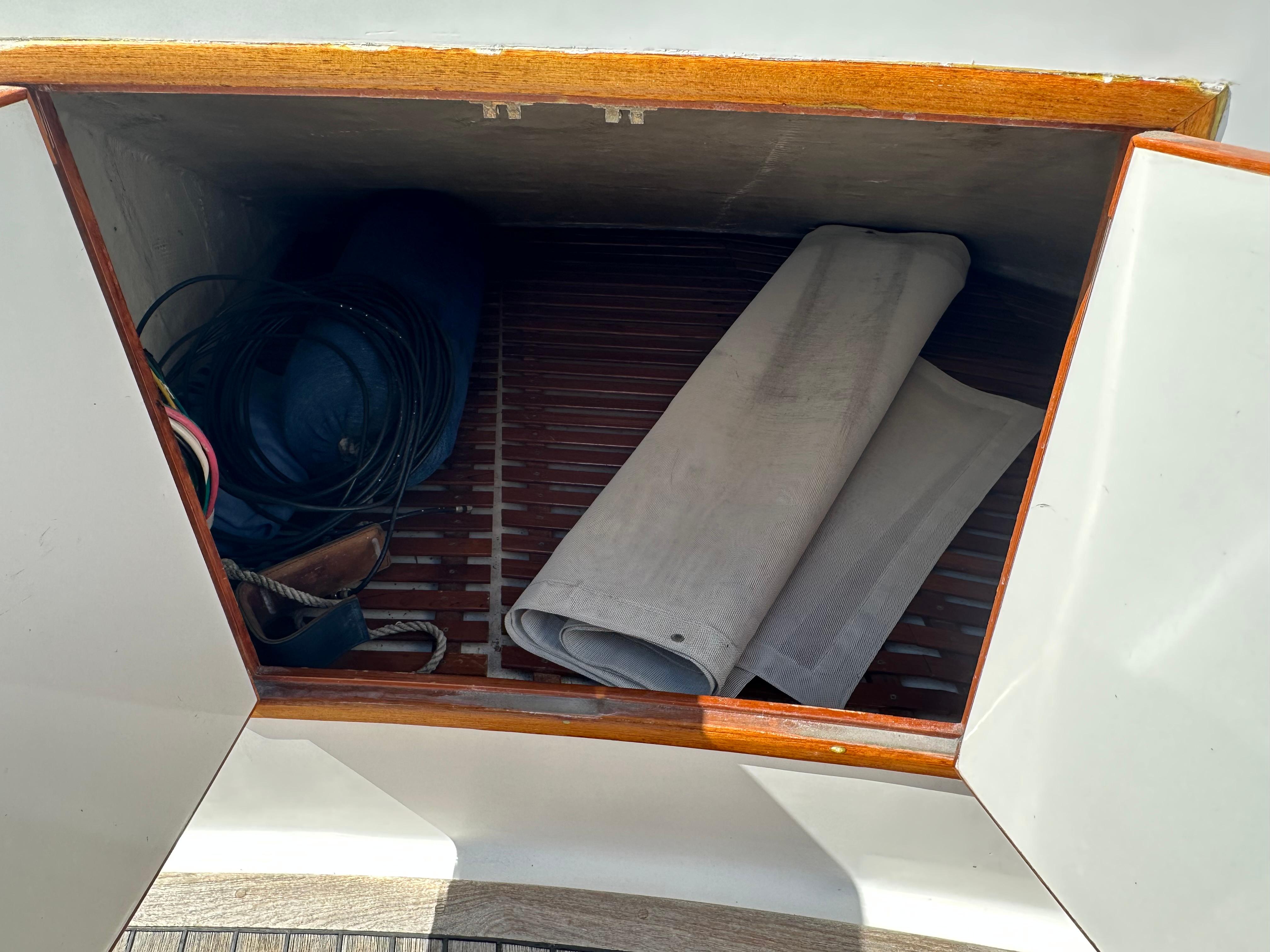 Storage compartment on 1985 Ocean Alexander Pilothouse yacht with coiled cables and rolled fabric.