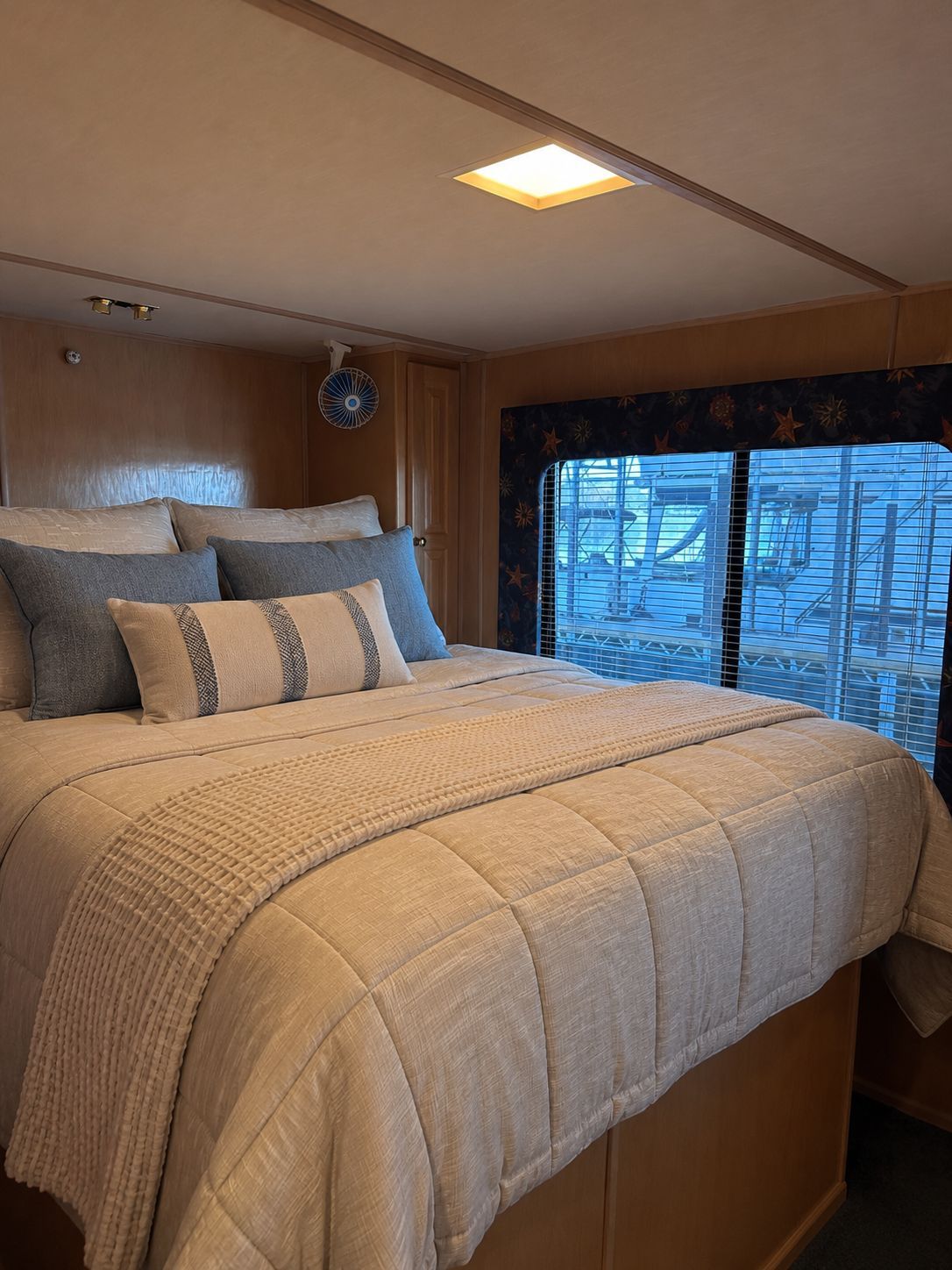 Interior of a yacht featuring a cozy bed and windows with an outside view.