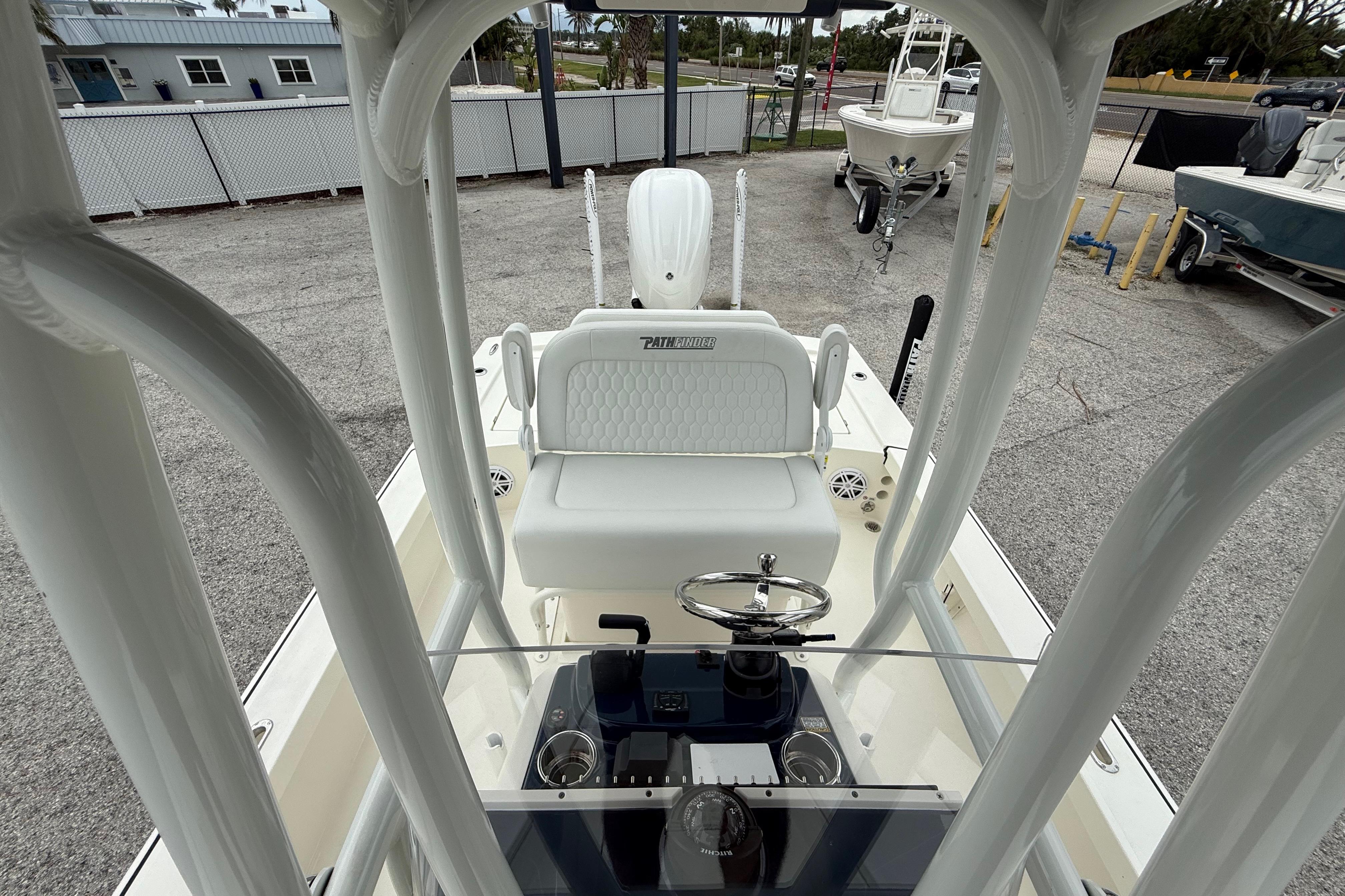 2026 Pathfinder 2300 HPS boat interior with steering console and seating, parked outdoors.