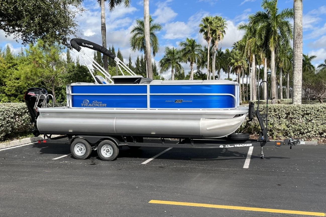2026 Sun Tracker Party Barge 20 DLX pontoon boat on trailer, parked in sunny lot.