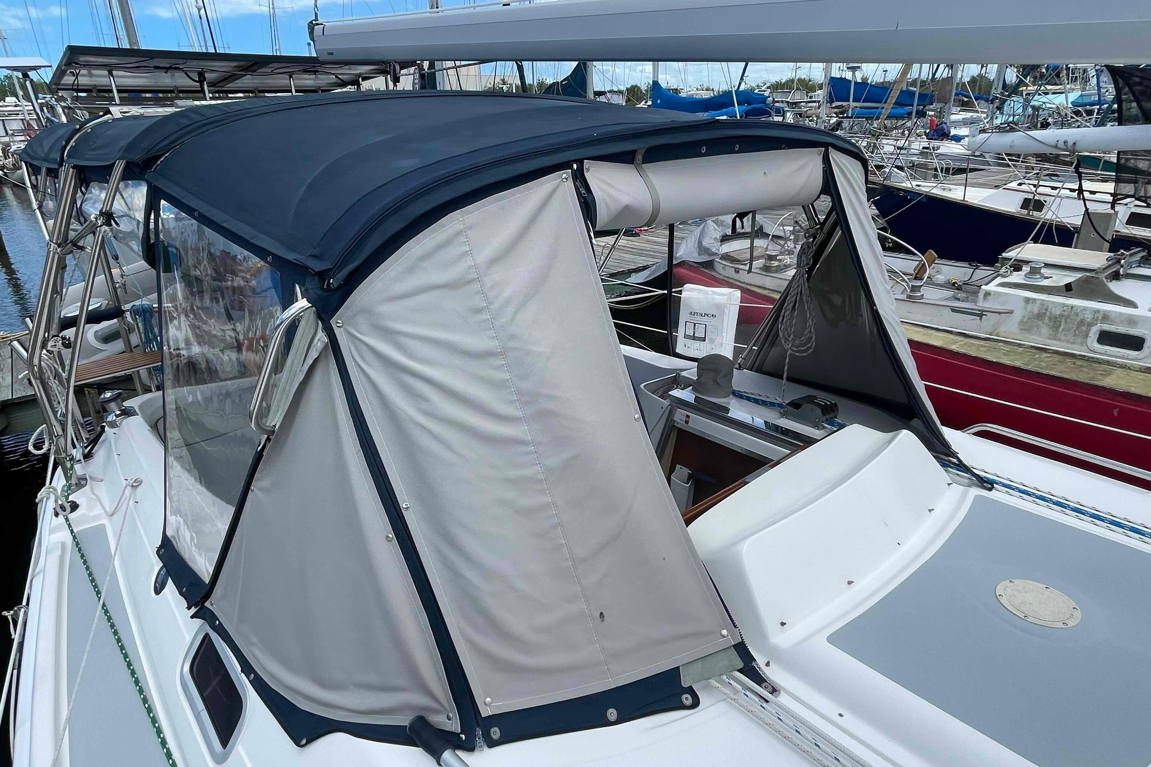 2004 Hunter 36 sailboat with blue and white cockpit enclosure in marina.