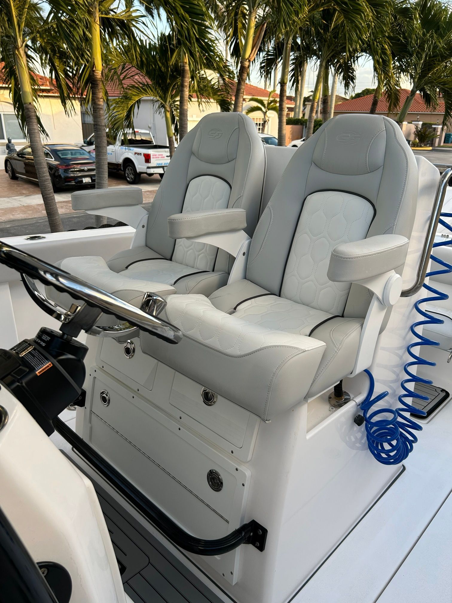 Two luxurious seats on a boat, surrounded by palm trees in the background.