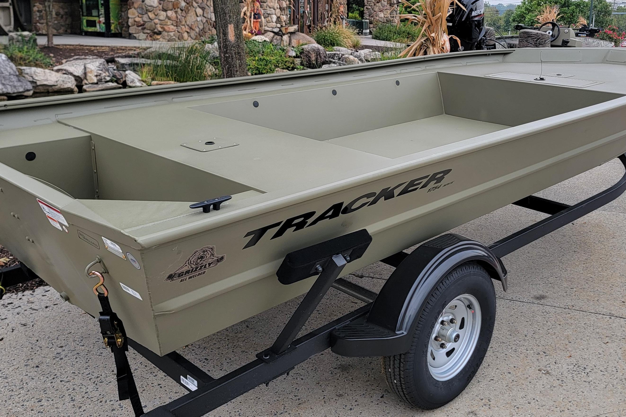 2026 Tracker Grizzly 1754 Utility boat on trailer, outdoors near stone building.