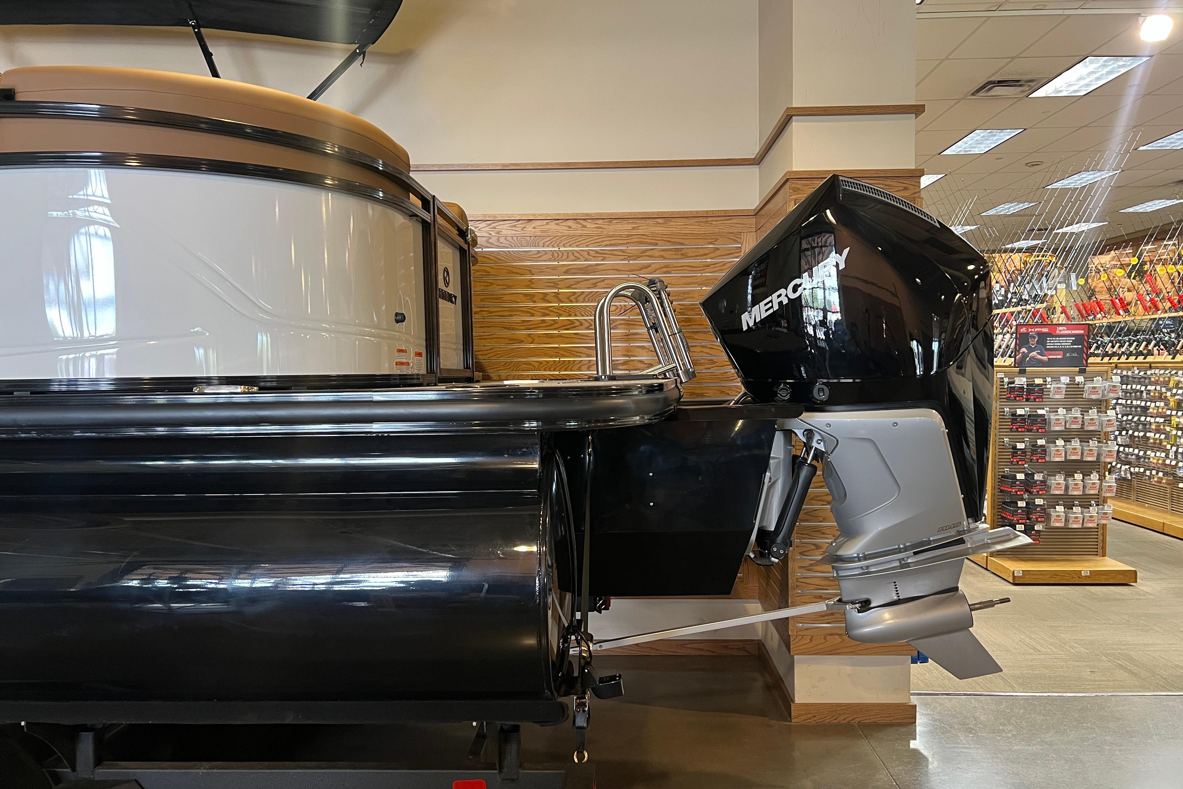 2026 Regency 230 DL pontoon boat with Mercury outboard motor displayed indoors.