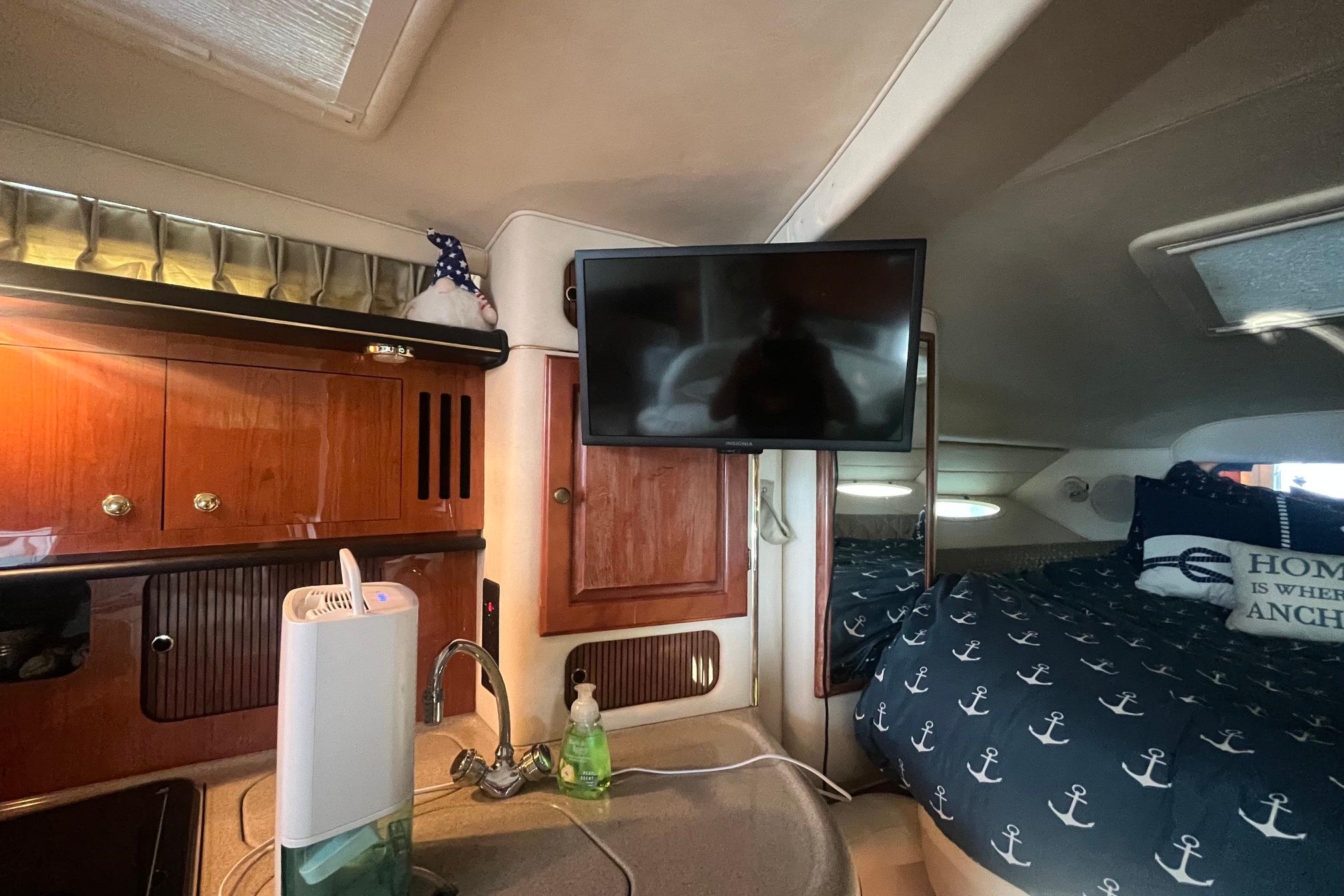 2001 Sea Ray 340 Sundancer cabin interior with kitchenette, TV, and nautical-themed bedding.